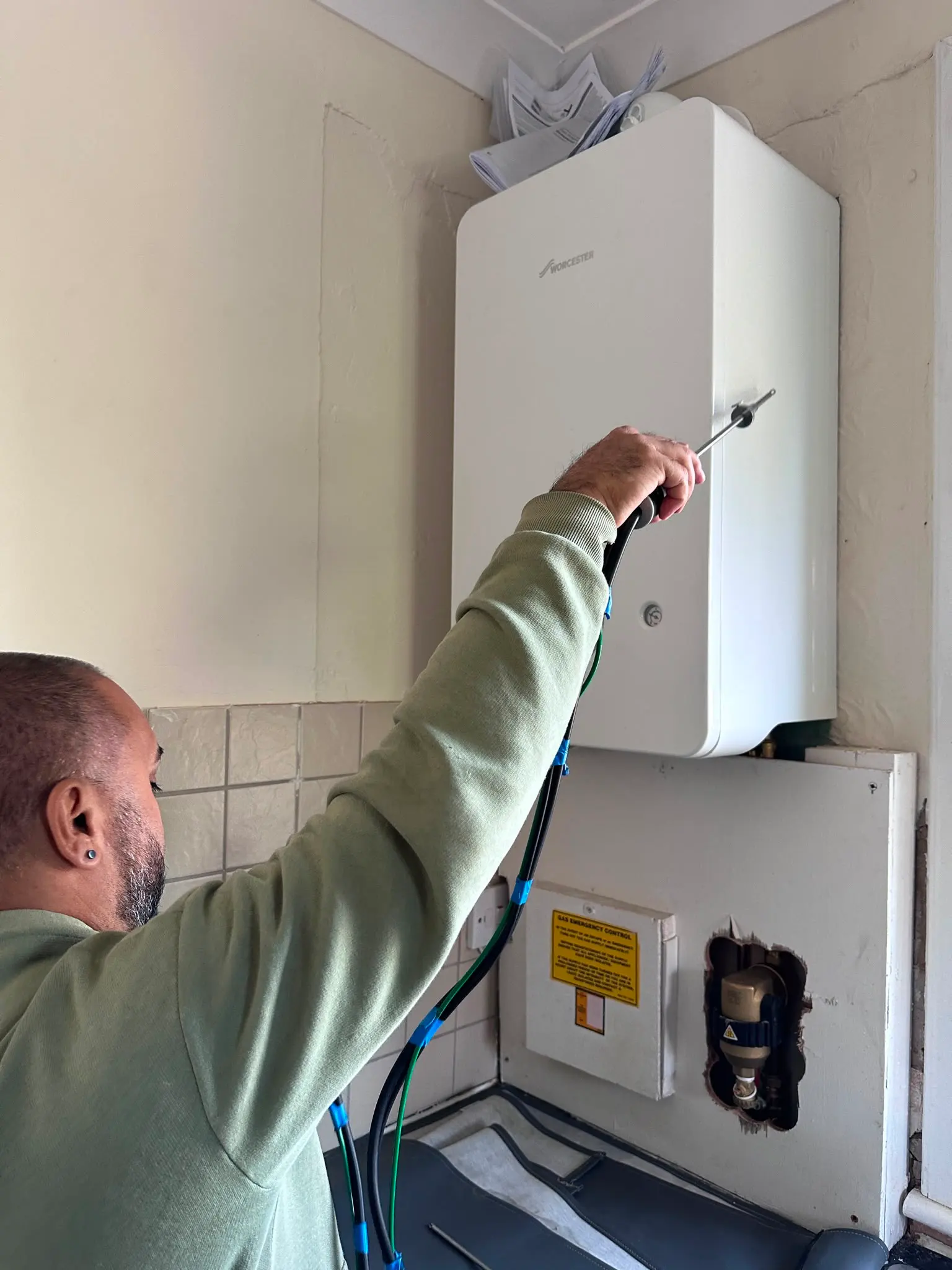 Local Gas Safe engineer carrying out professional boiler servicing and maintenance testing on a wall-mounted Worcester boiler.