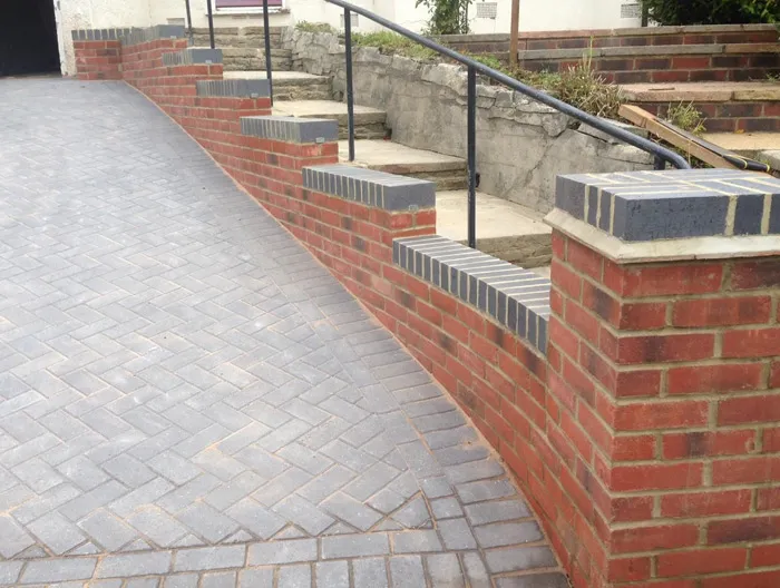 Newly completed grey block paving driveway and a red brick garden wall with dark grey caps, demonstrating high-quality hard landscaping.