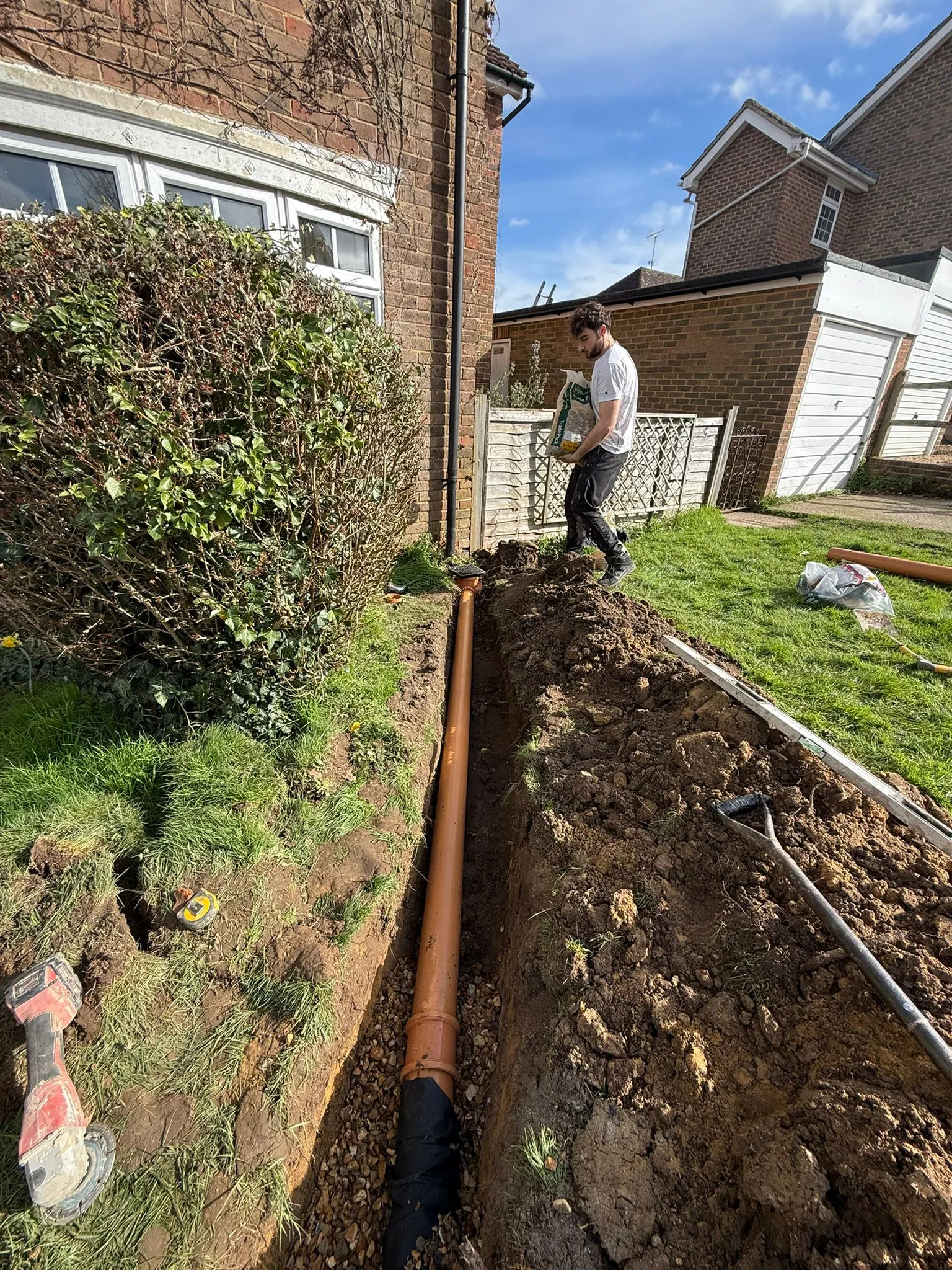 Professional drainage installation showing a new pipe in a garden trench by Drainage South Ltd.