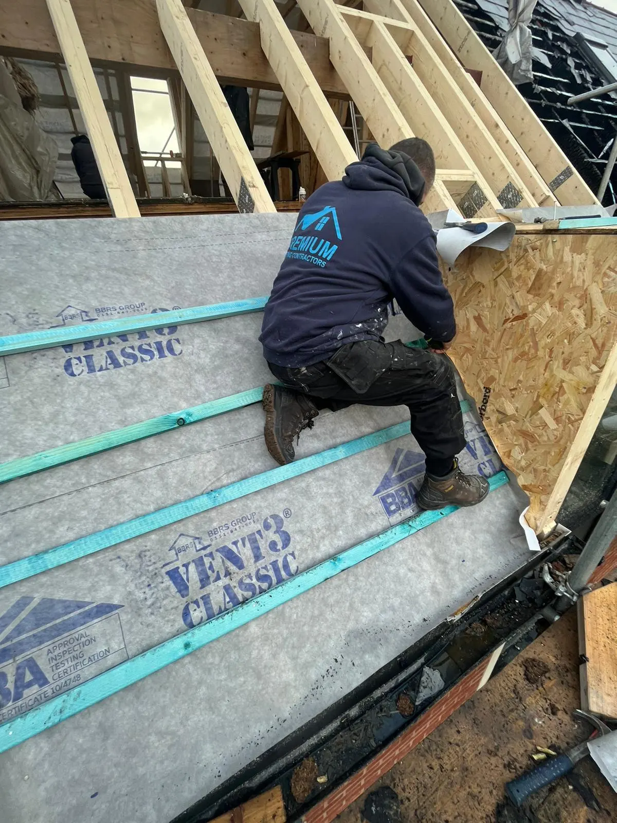 A roofer from Premium Roofing Contractors installing Vent3 breathable membrane and roof battens on a new timber roof build
