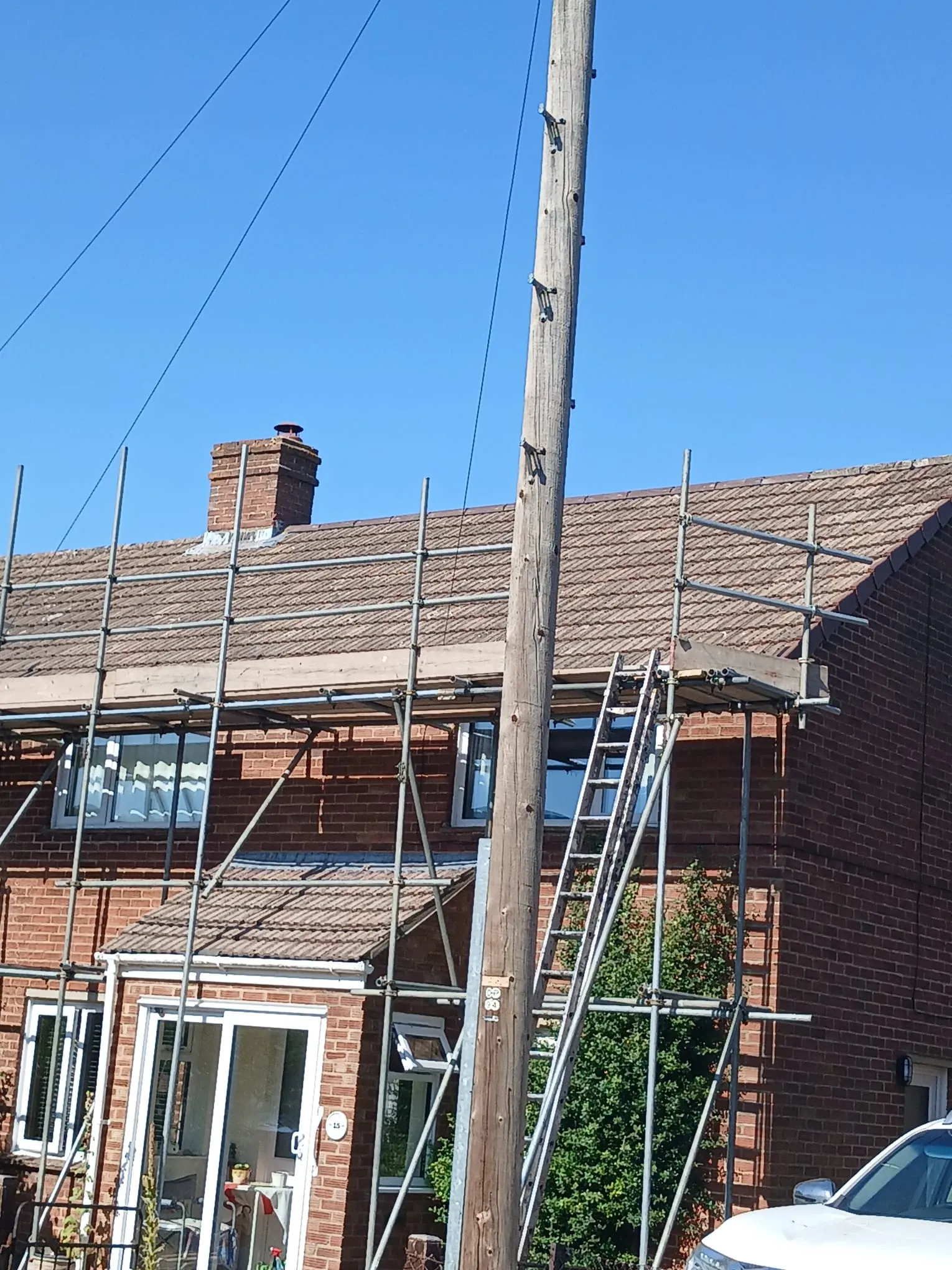 Scaffolding erected on a two-storey brick house for roof repairs and tile replacement