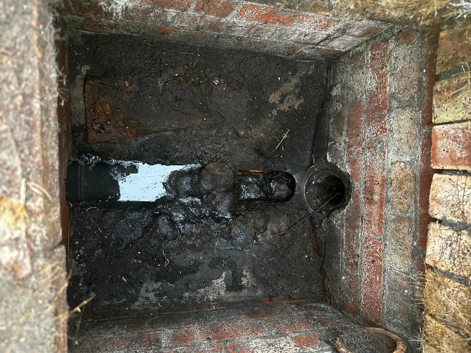 A photo of a blocked outdoor drain with standing dirty water and heavy sludge, indicative of a significant drainage problem in Skipton.