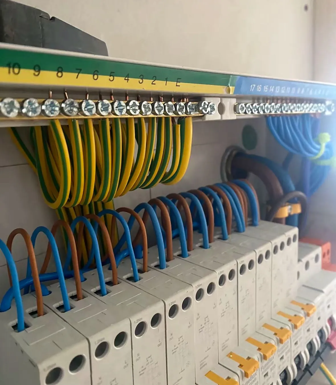 A close-up of a professionally wired consumer unit showing circuit breakers and coloured electrical wiring.