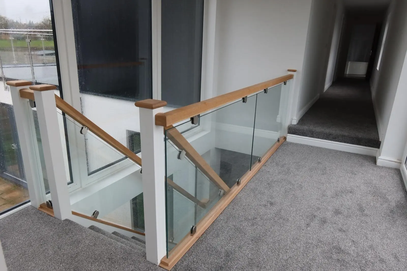 Modern glass staircase and smooth white plastered walls in a thermally efficient home following internal wall insulation