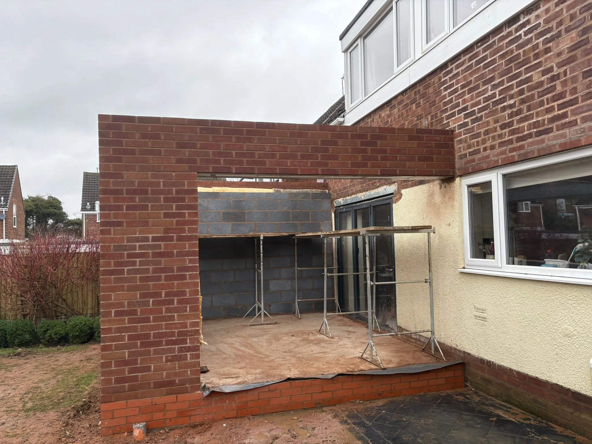 A home extension under construction, with new brick walls and internal blockwork visible, demonstrating the early stages of a single-storey build.