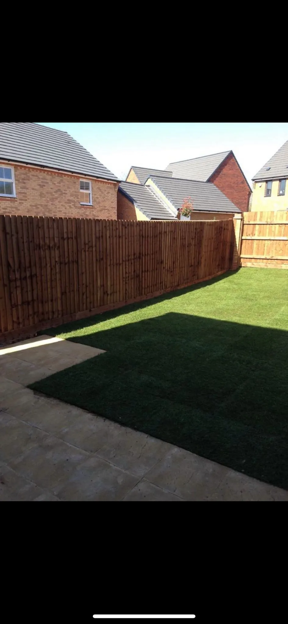 Newly laid turf lawn, paved patio, and new closeboard fence in a modern garden.