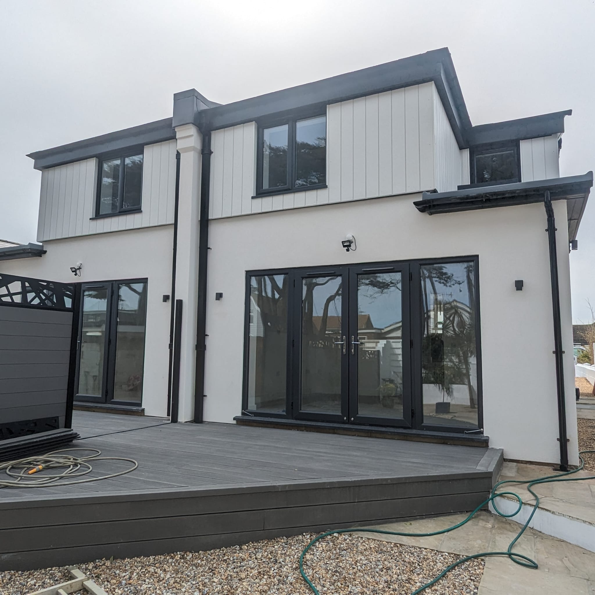 A modern residential property in Sussex with professional white external rendering and grey bifold doors.