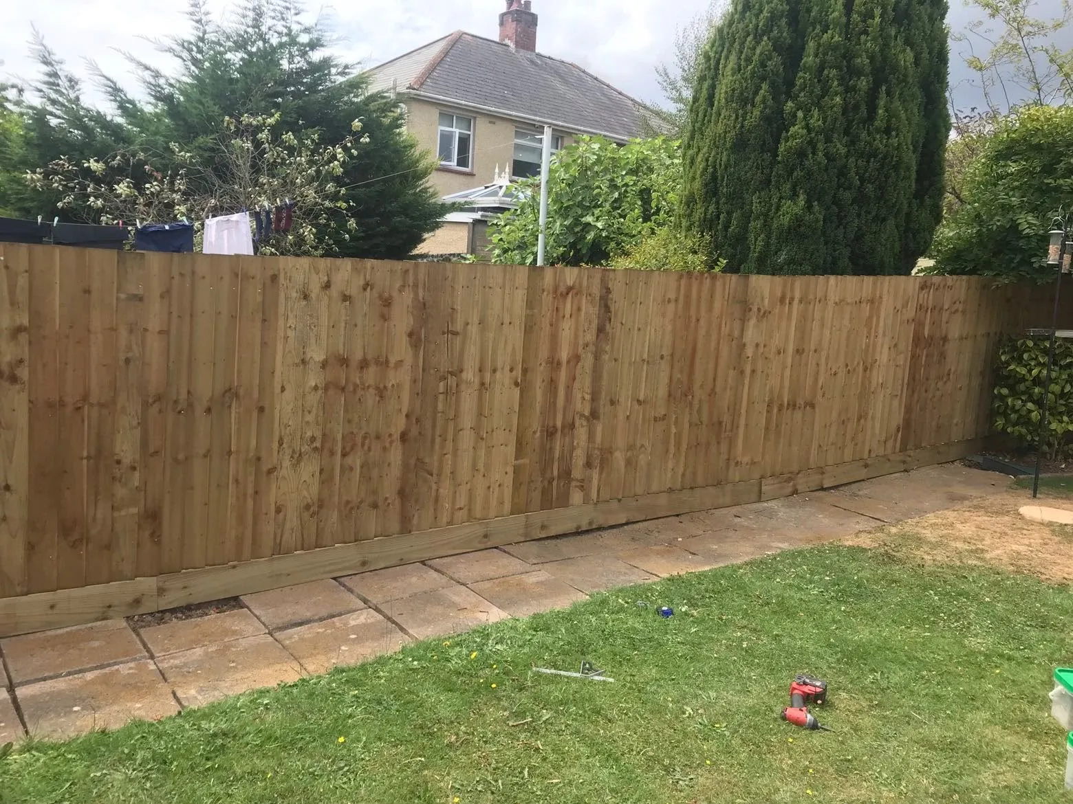 A newly installed vertical featheredge fence with bottom gravel boards installed along a garden patio by JDP Outdoor Solutions