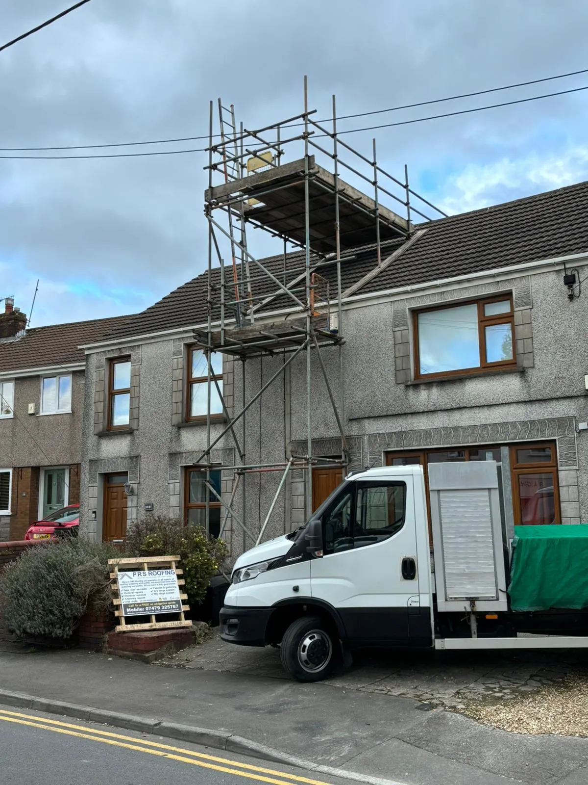 Scaffolding and a professional roofing van at a residential property for roof repairs and maintenance.