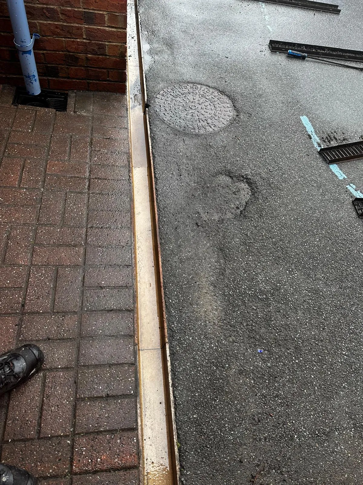 A picture of an external drain system with a manhole, channel drain, and gulley, indicating a blocked drain or recent unblocking service.
