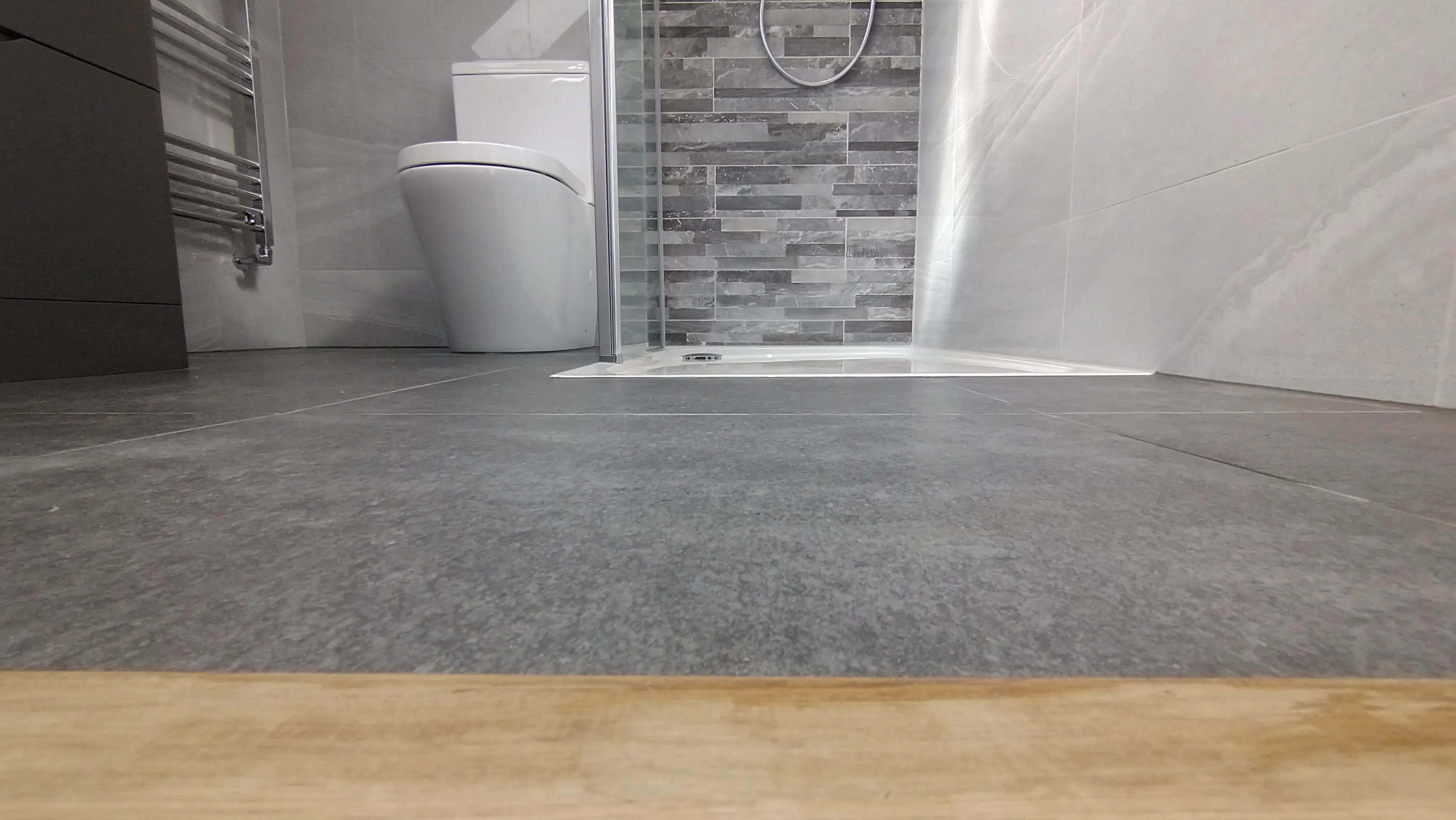 Bespoke luxury bathroom installation in Plymouth featuring modern grey tiling and a walk-in shower area.
