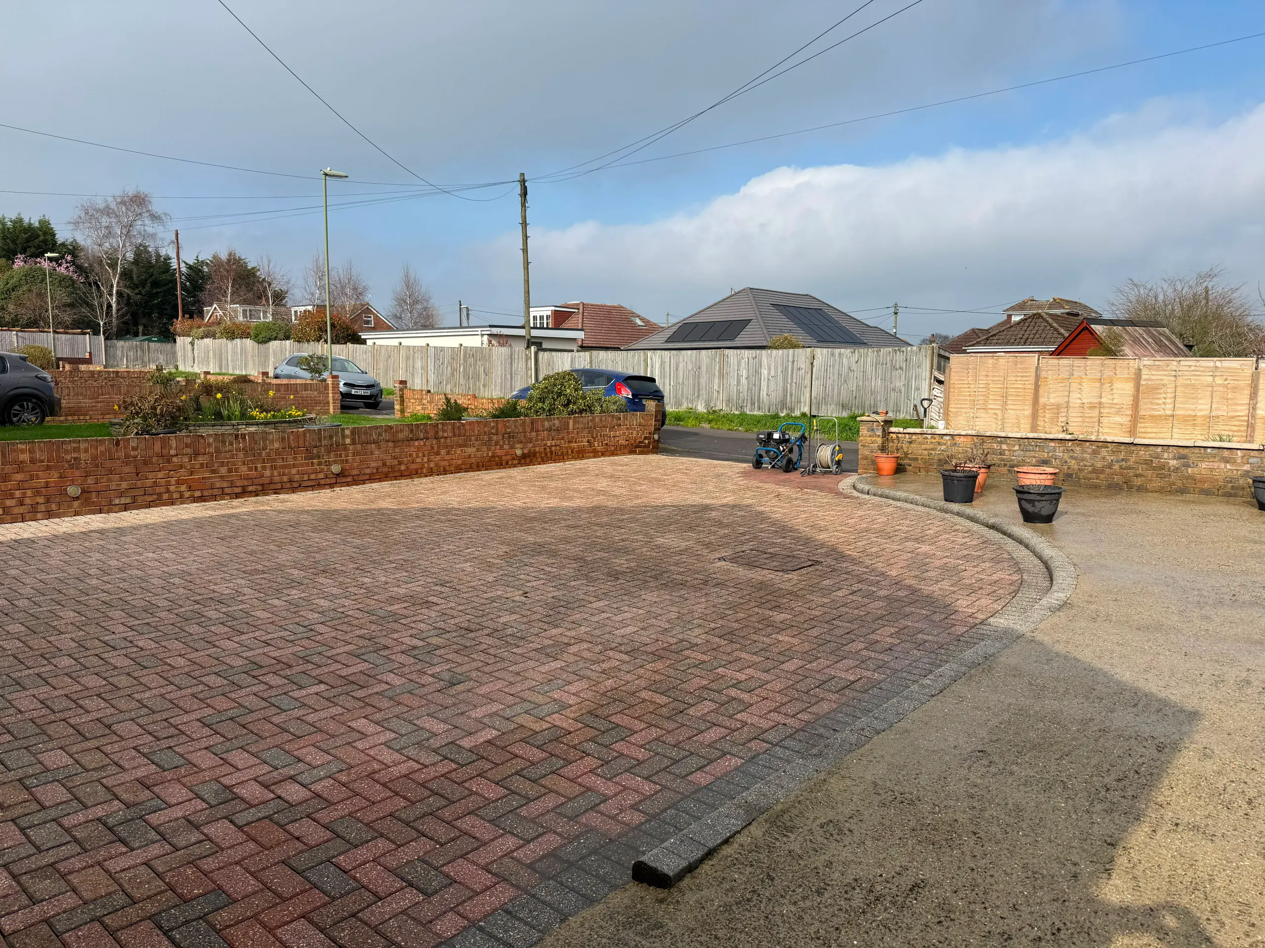 Freshly cleaned block paved driveway showing restored red and grey bricks after professional pressure washing.