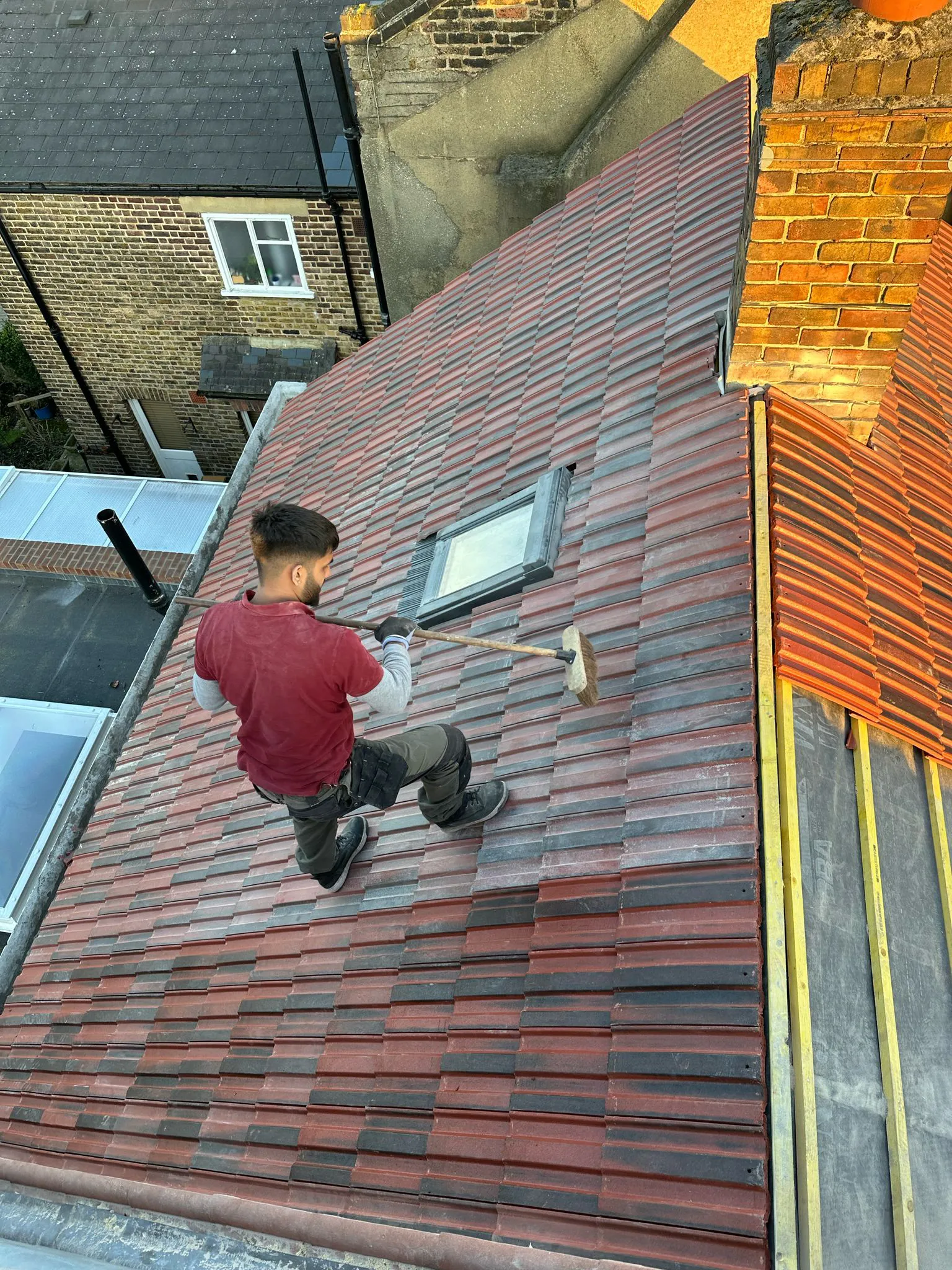 Roofer finishing installation of new interlocking roof tiles on a pitched roof in Plymouth