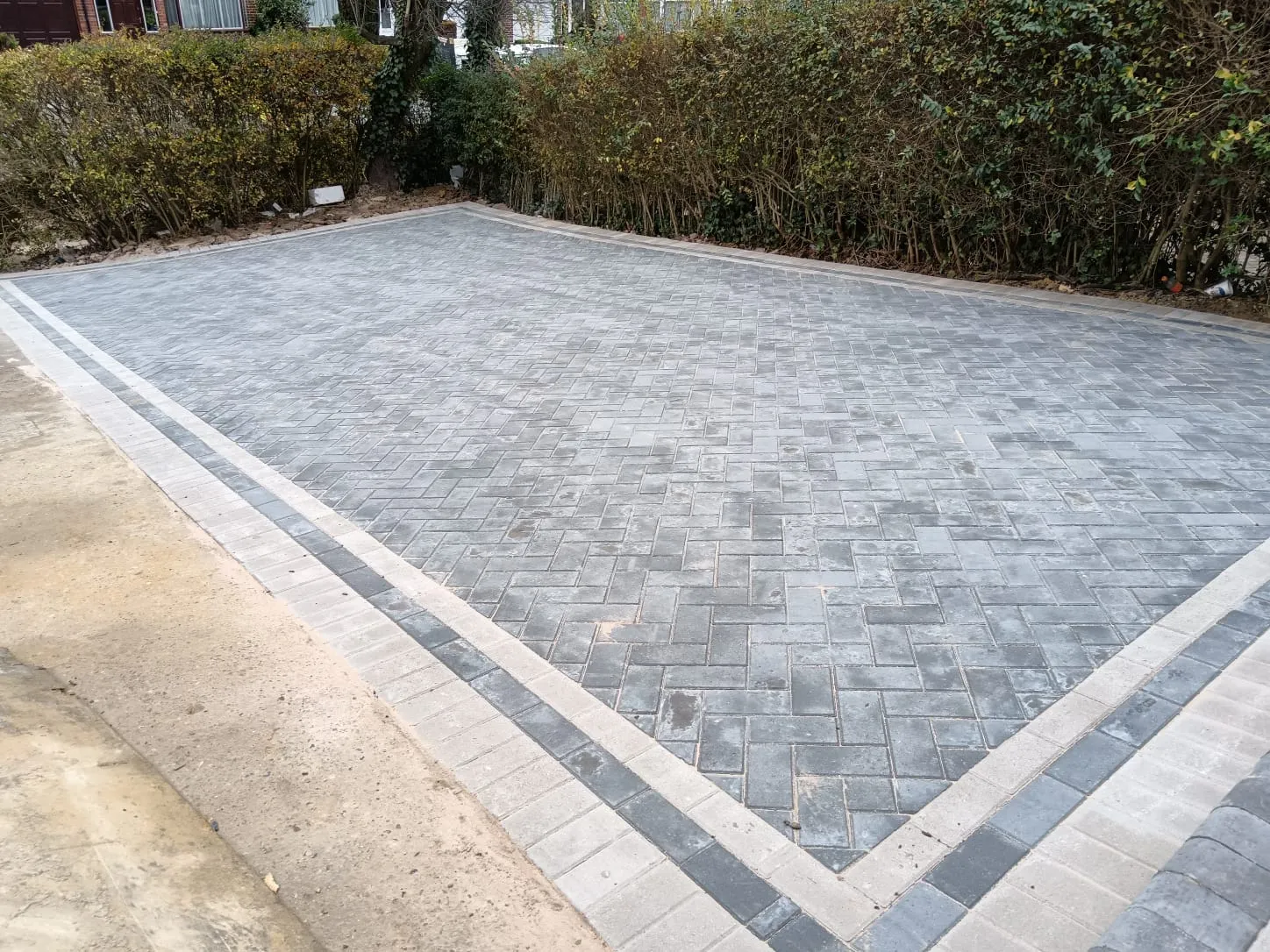 A newly laid block paved driveway in a herringbone pattern with a contrasting two-tone block border.