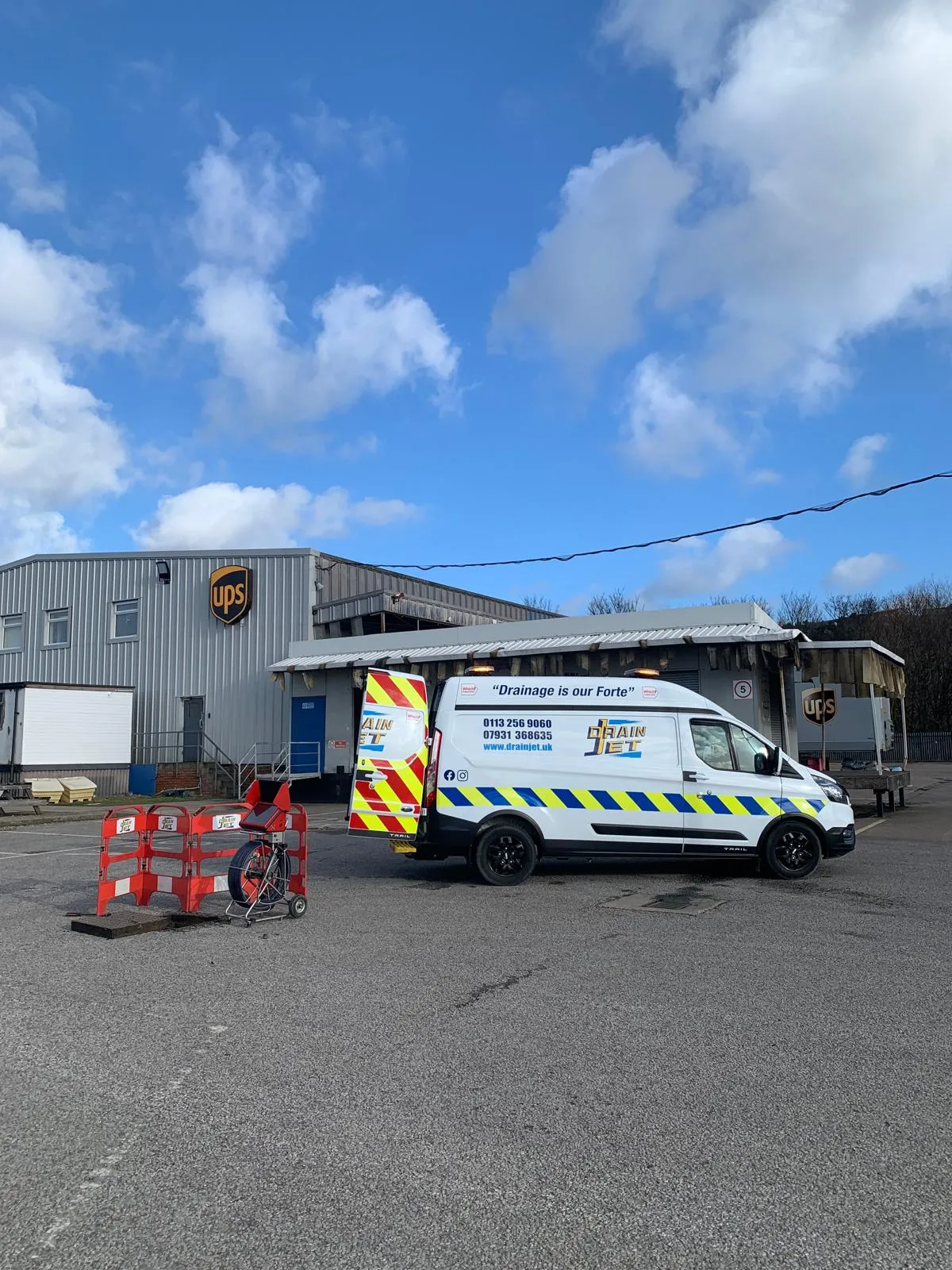 Drain Jet van and drainage equipment outside a commercial UPS facility for drain maintenance and repairs.