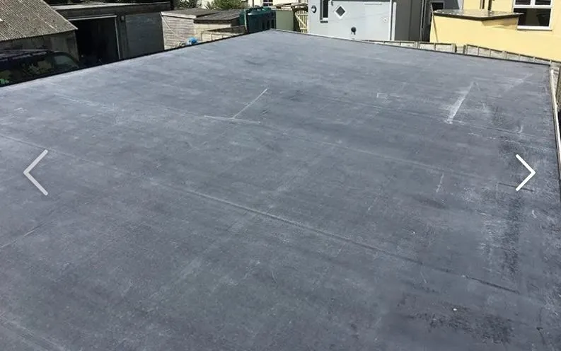 An overhead view of a newly installed dark grey flat roof, showcasing its seamless finish and quality workmanship.