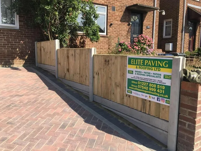 Newly laid red block paving driveway next to a modern timber fence with a sign for Elite Paving & Roofing LTD in Canterbury, Kent.