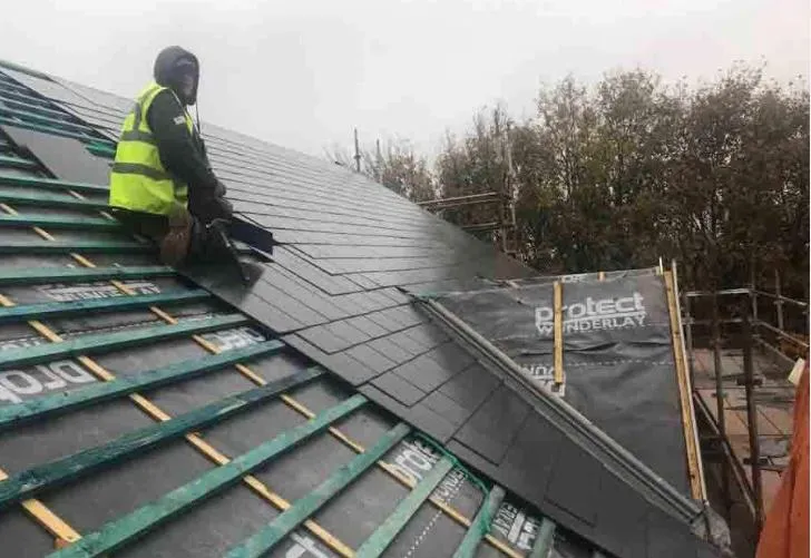 Roofer working on a new tiled roof installation with visible battens and breathable membrane.