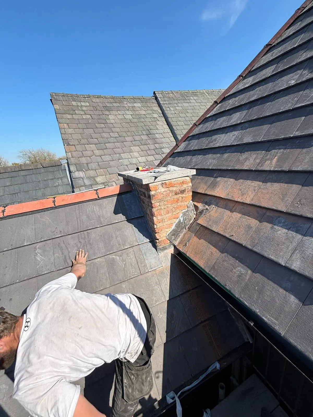 Expert local roofer carrying out slate roof repairs and inspecting chimney leadwork in Cheshire