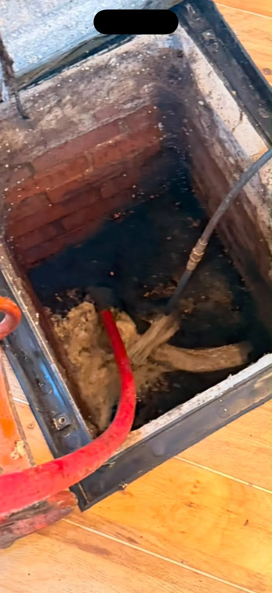 High-pressure water jetting hose clearing a blocked brick inspection chamber in Slough
