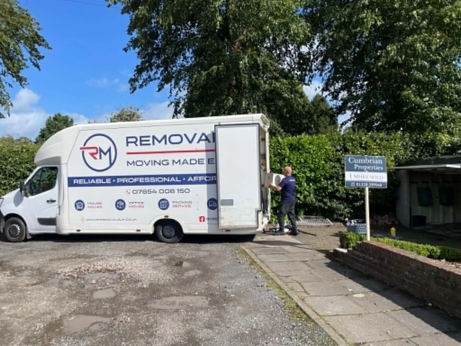 RM Removals van and mover loading furniture outside a residential property in Cumbria