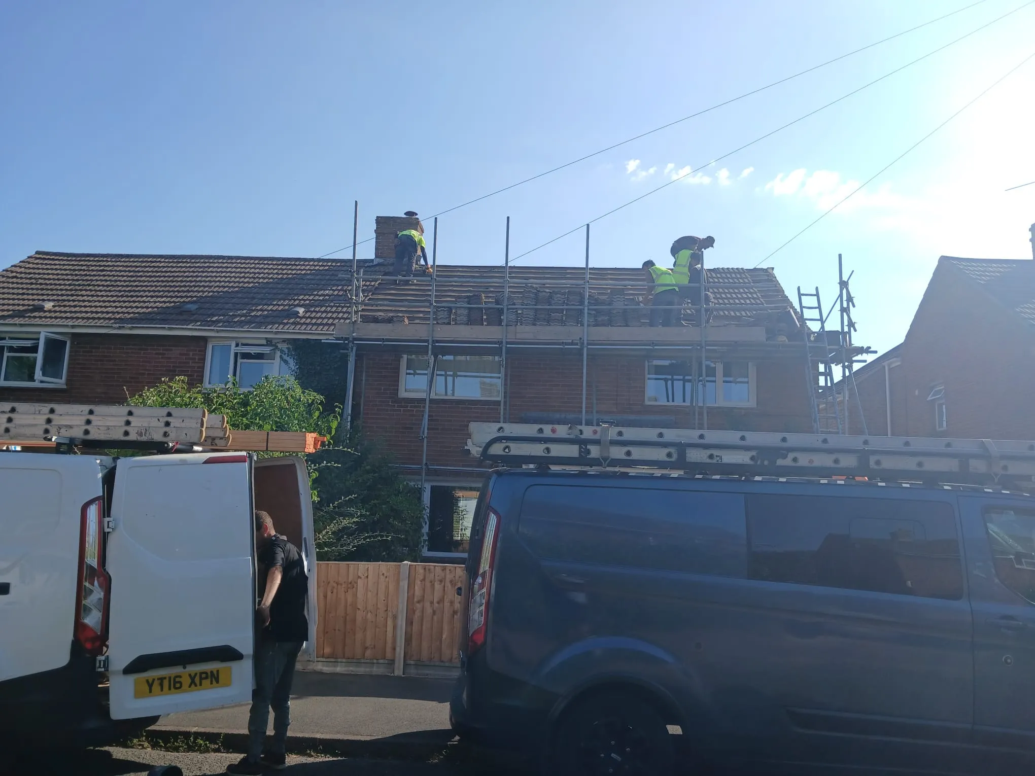 Roofers carrying out a full tiled roof replacement and re-roofing on a semi-detached residential property