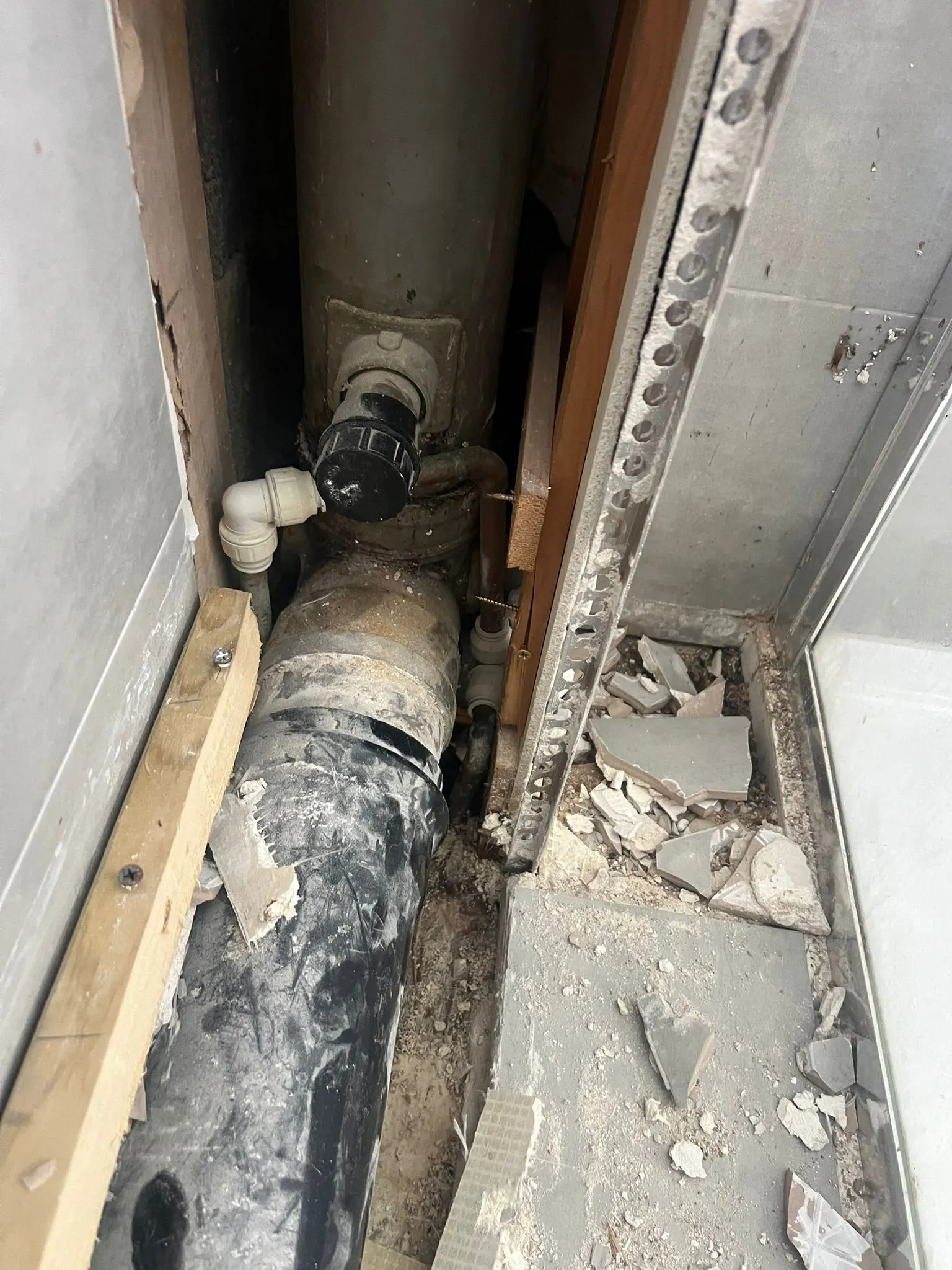 Exposed pipes and debris during a plumbing repair in a residential property