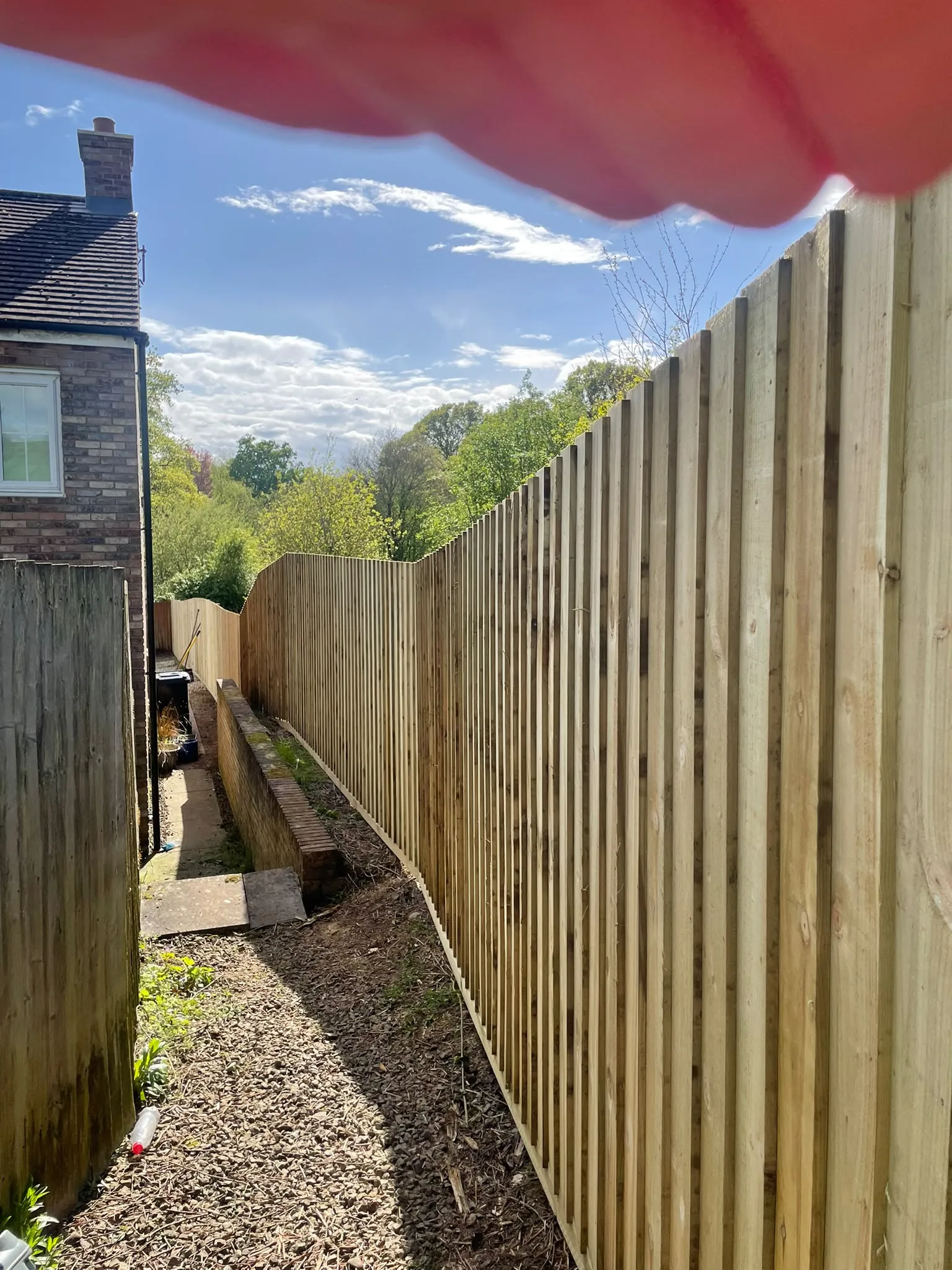 Newly fitted featheredge timber boundary fence installed on a sloping residential garden