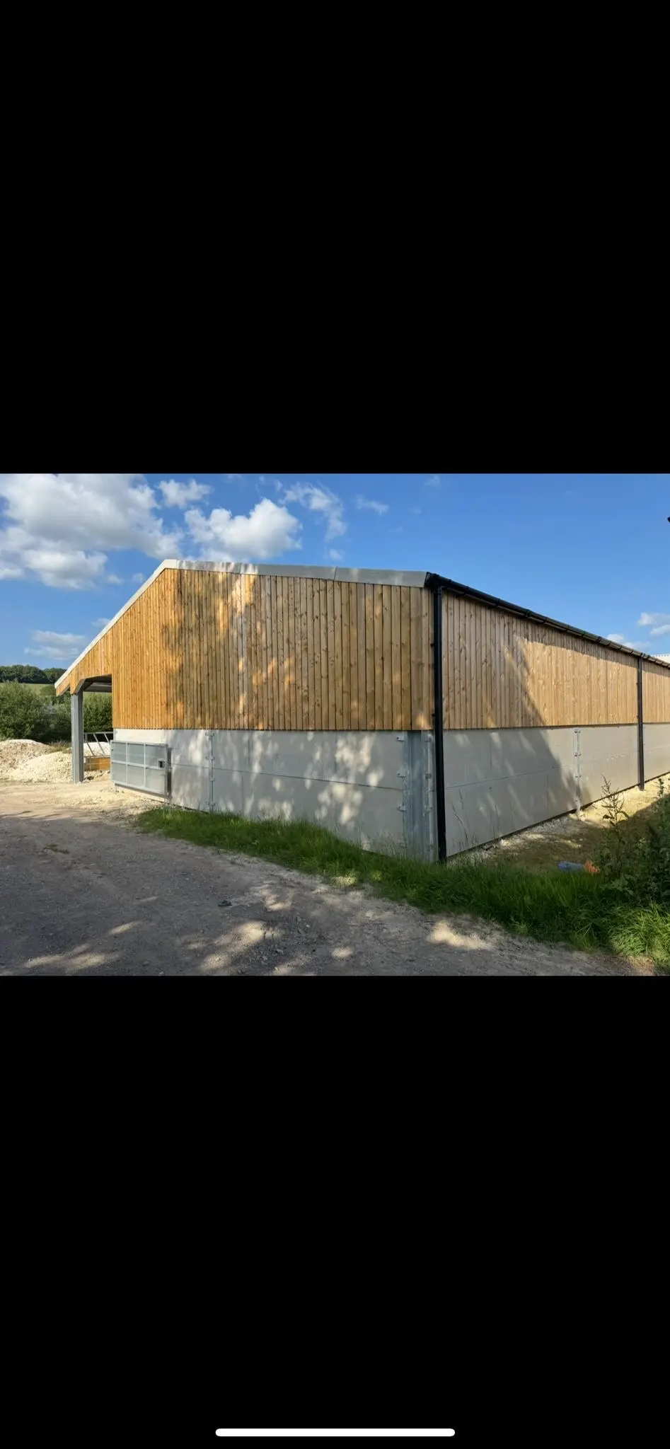A completed agricultural building with concrete panels and timber cladding, constructed by ER3 Group LTD.