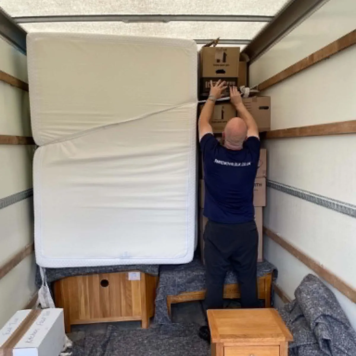 RM Removals crew member securing boxes and protected furniture inside a removal vehicle
