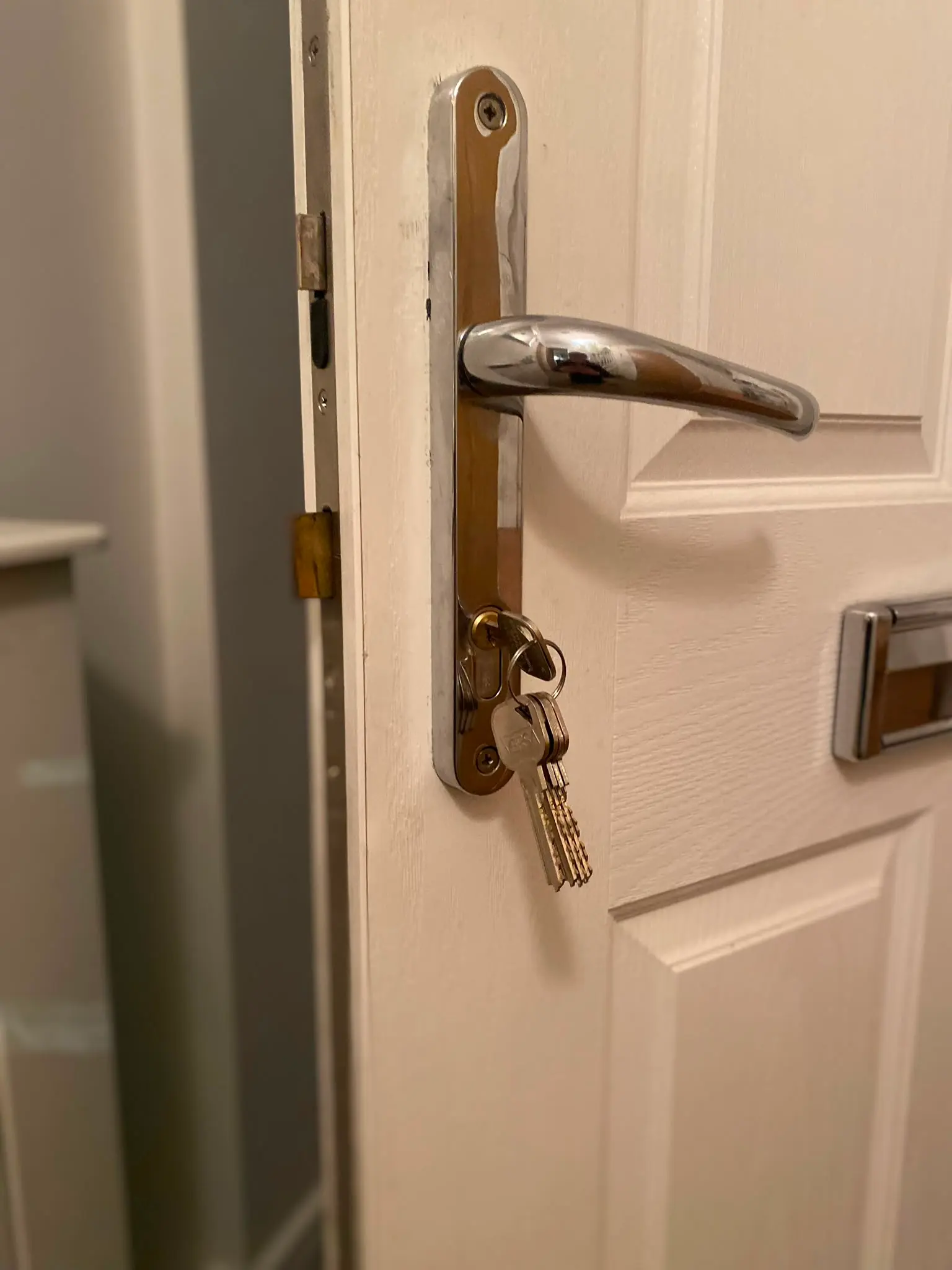 Keys in a Euro cylinder lock and chrome door handle on a white uPVC door