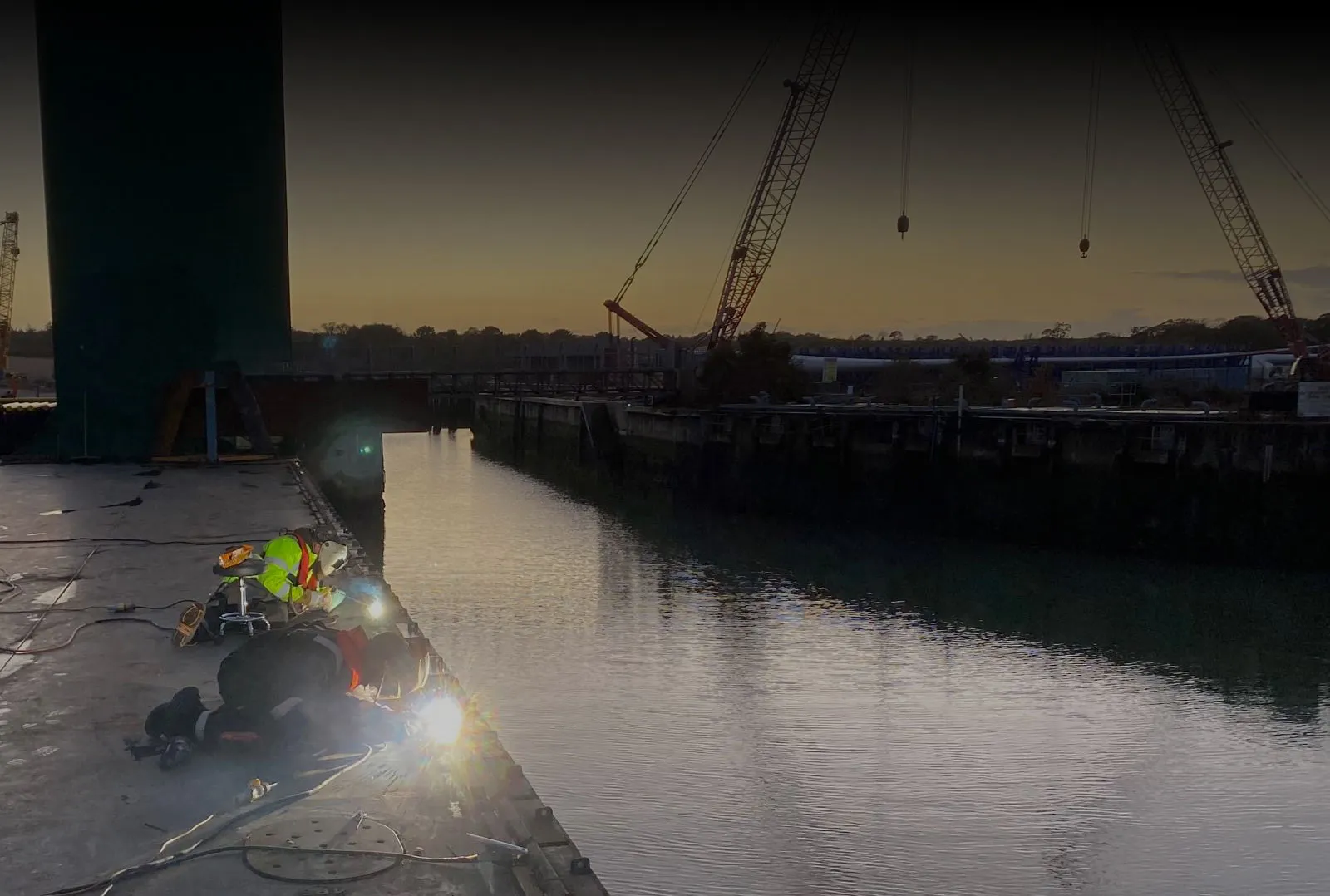 Coded welders working on marine fabrication and ship repairs at a dockside in Southampton.