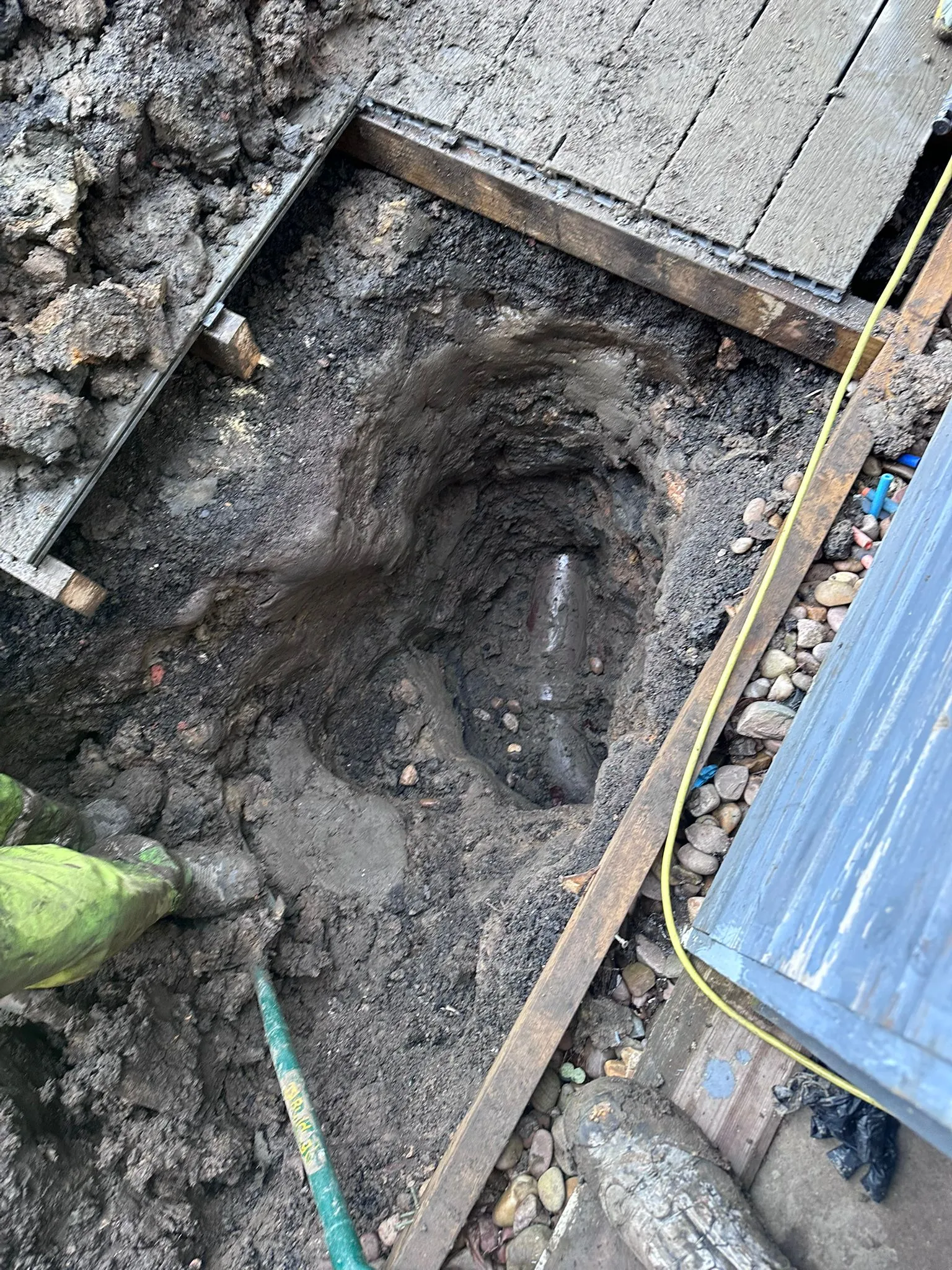 Drainage excavation work showing an exposed underground pipe for repair in Macclesfield.