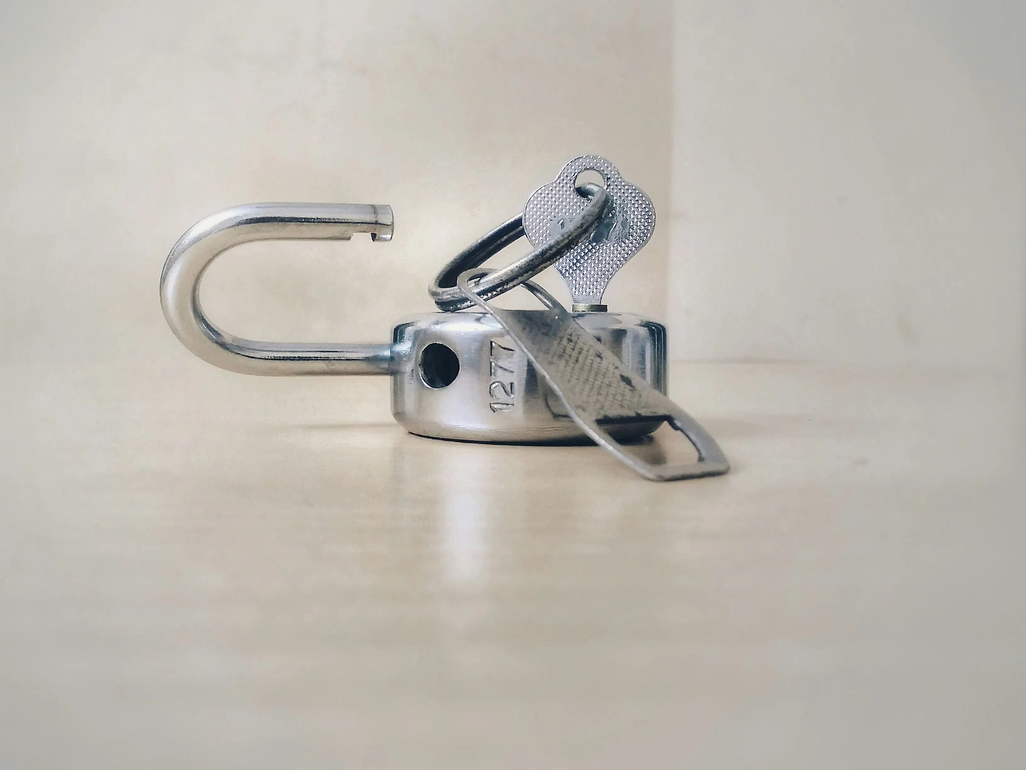 An open silver padlock with its key, symbolising lock change or upgrade services.