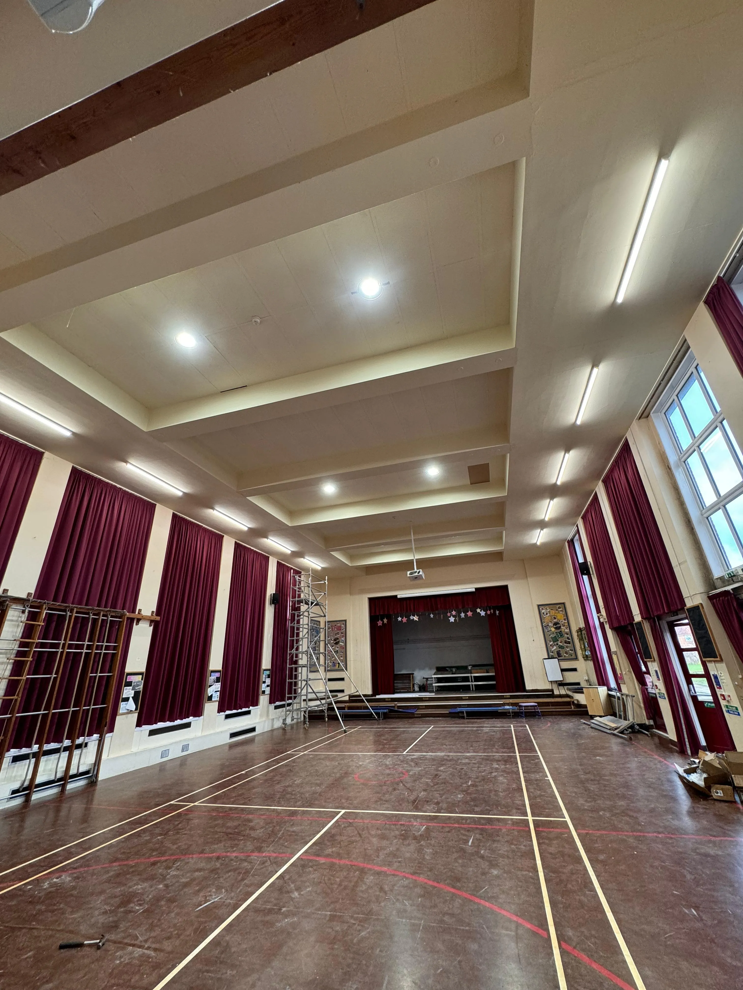 High-level commercial electrical maintenance and lighting installation in a large hall using scaffolding.