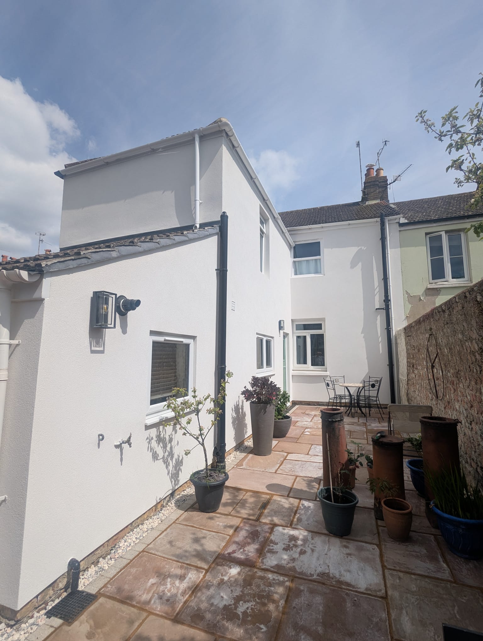 Freshly rendered white exterior walls of a house in a patio area.