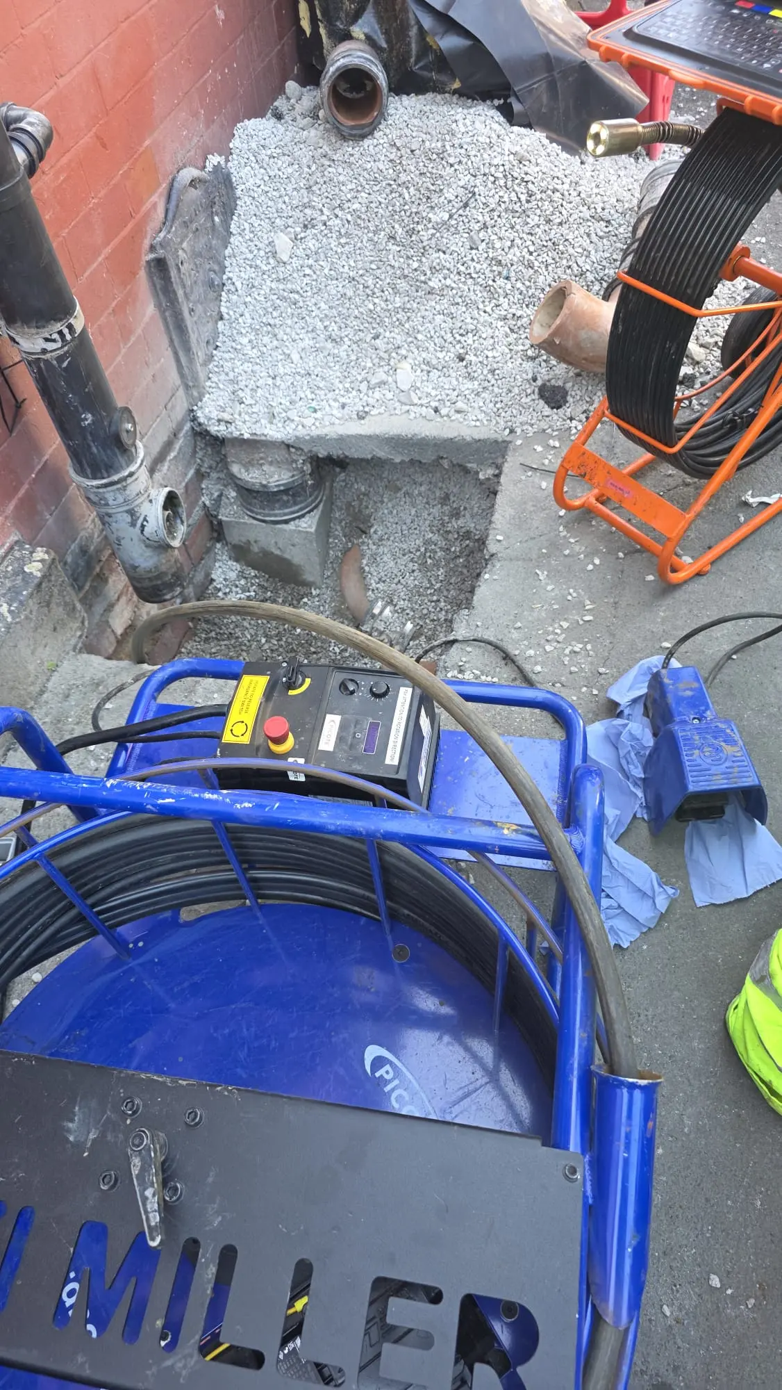 APJ Drainage site setup showing a Picote mechanical milling unit and CCTV drain survey camera next to an excavated pipe and soil stack.
