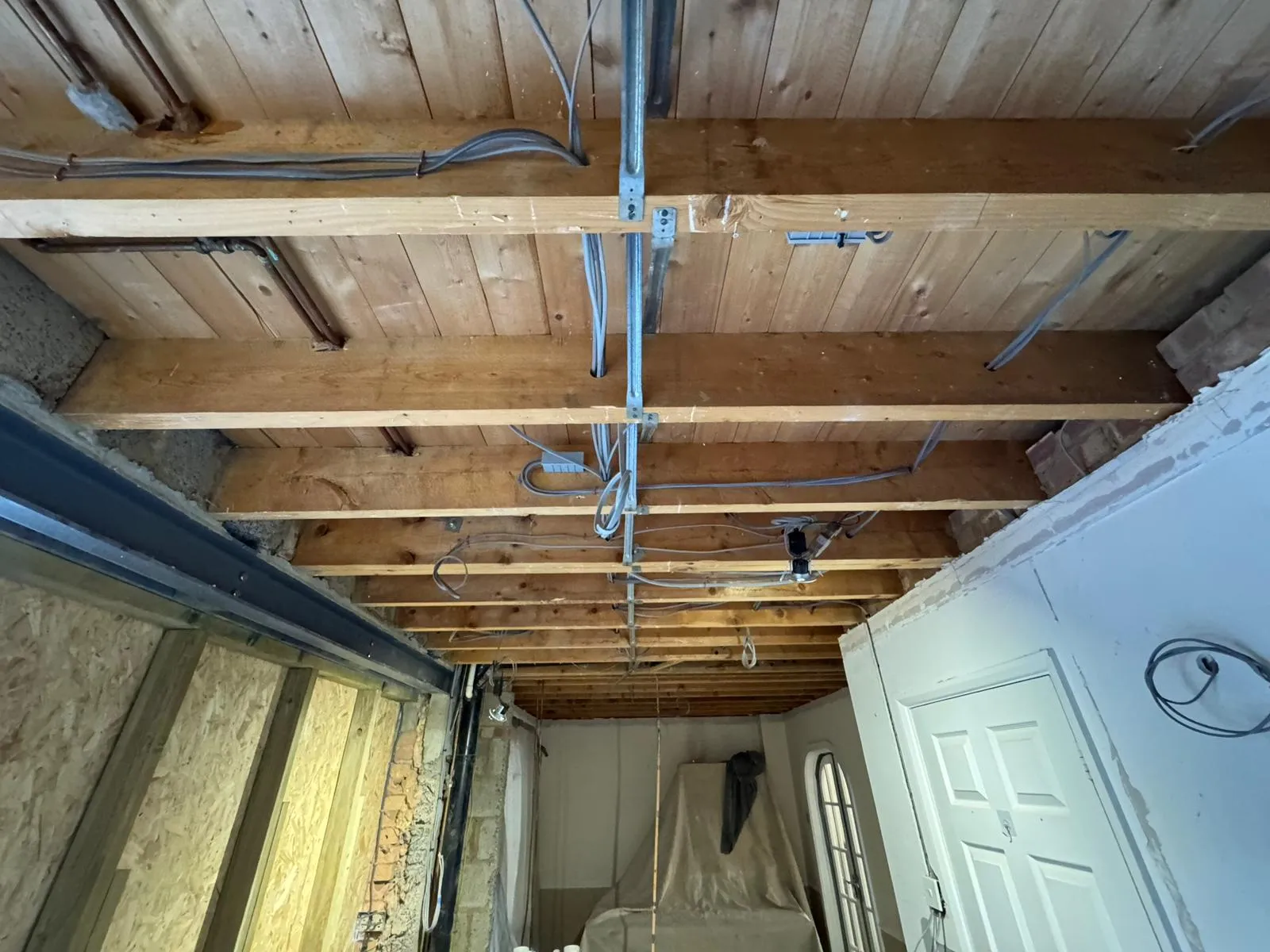 First fix electrical wiring and plumbing pipes installed in ceiling joists during a house rewire in Suffolk.