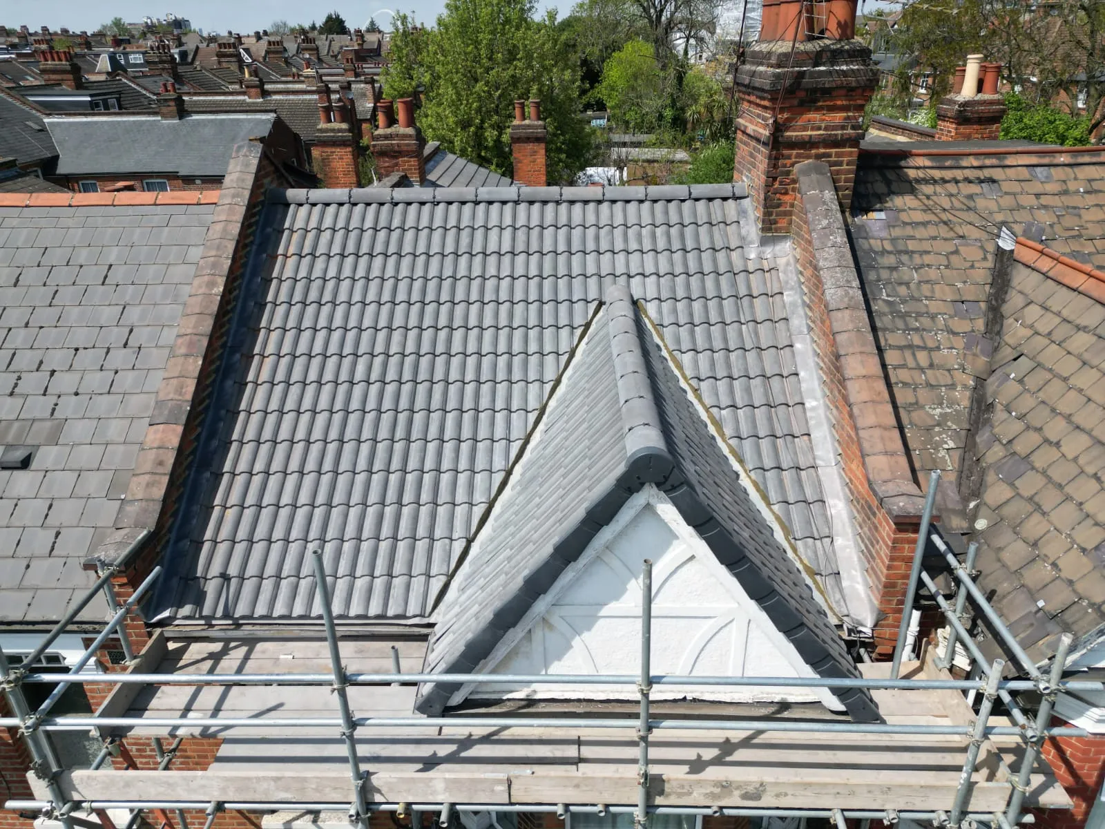 Newly installed grey tiled pitched roof and dormer window.