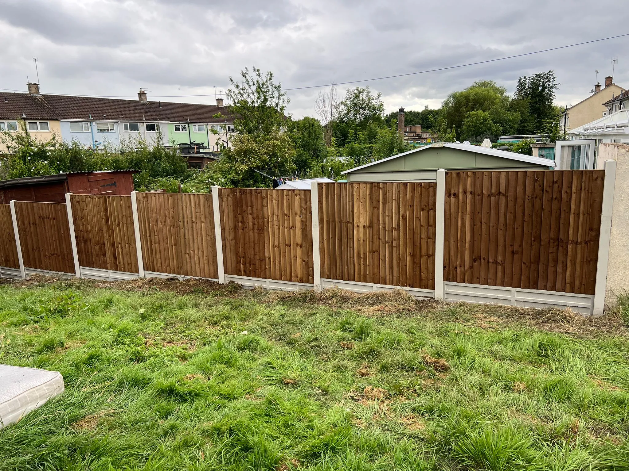 A new featheredge wooden fence with concrete posts and gravel boards in a garden.