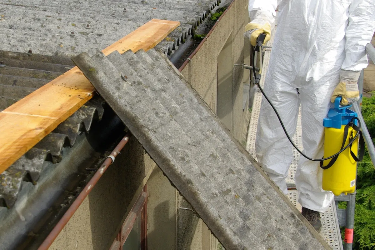 Professional asbestos roof removal being carried out by a specialist in protective gear.