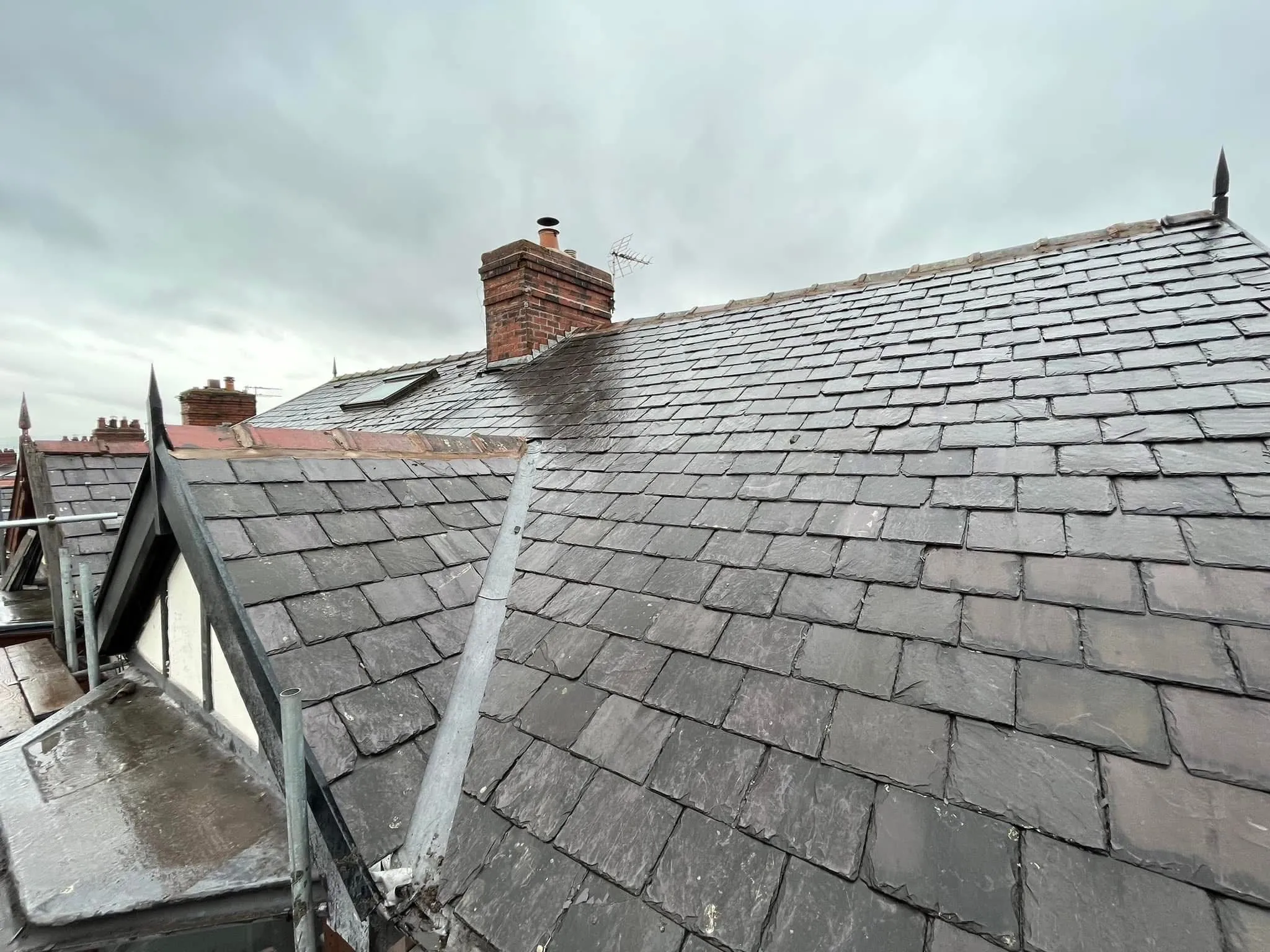 Professional slate roofing and chimney leadwork on a pitched roof in Lancashire.
