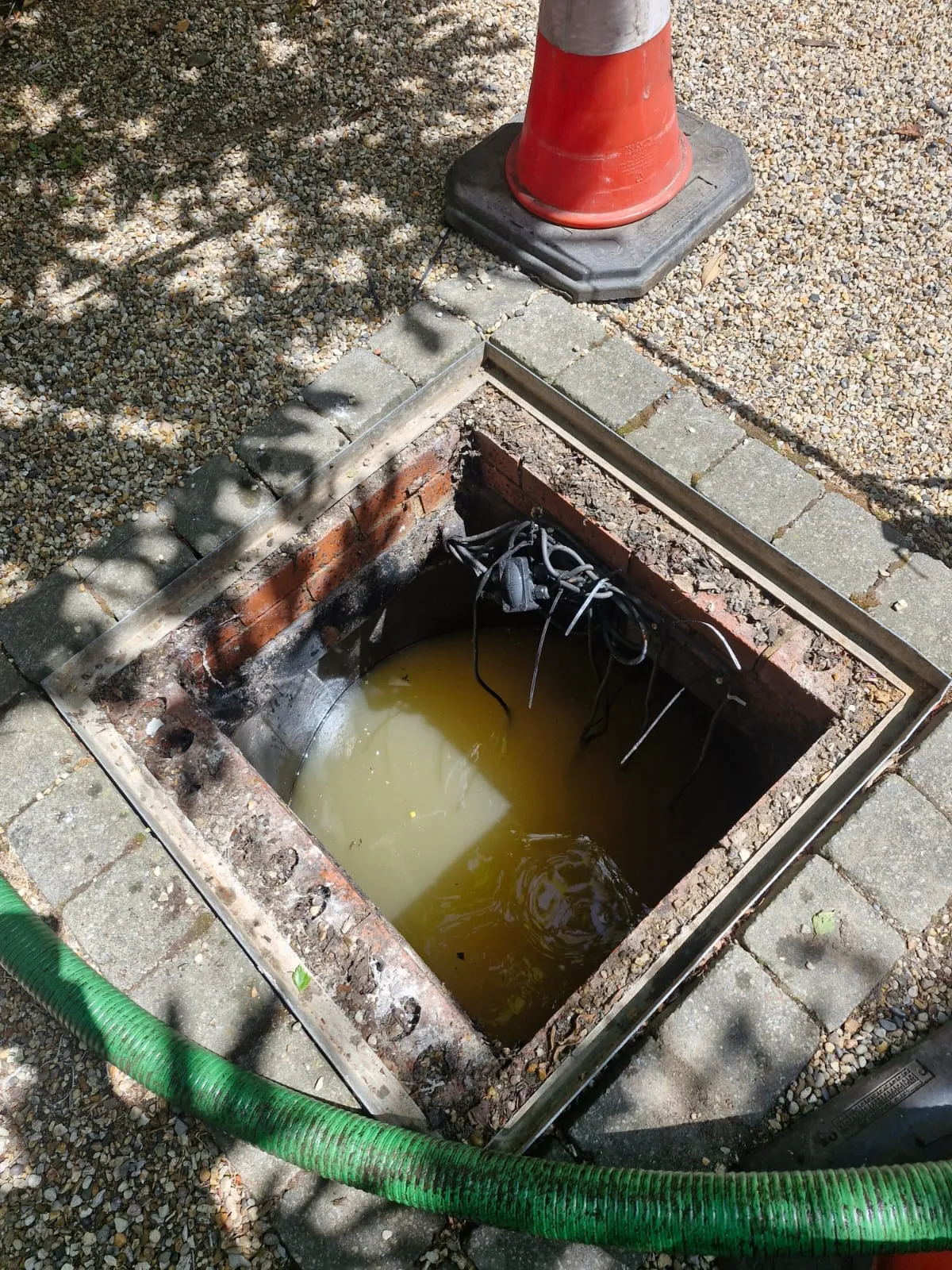 A blocked and flooded drain manhole with float switches visible, ready for unblocking by Roberts Drainage Ltd.