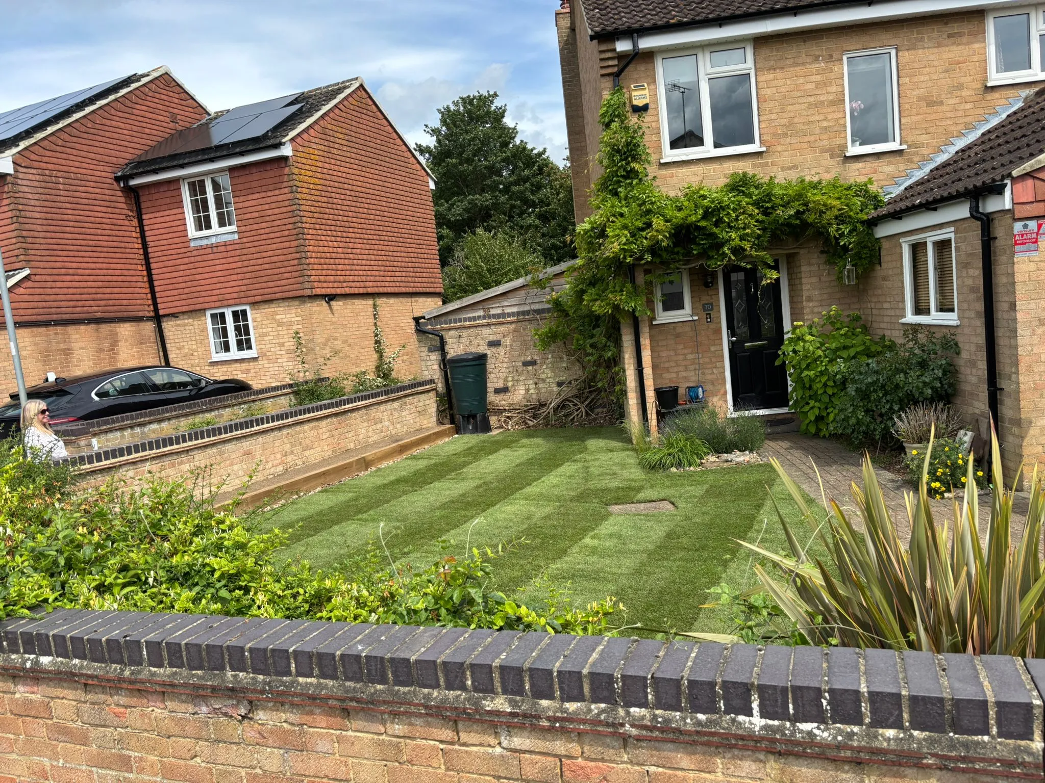 A freshly turfed front garden with a neat striped finish and surrounding garden brickwork.