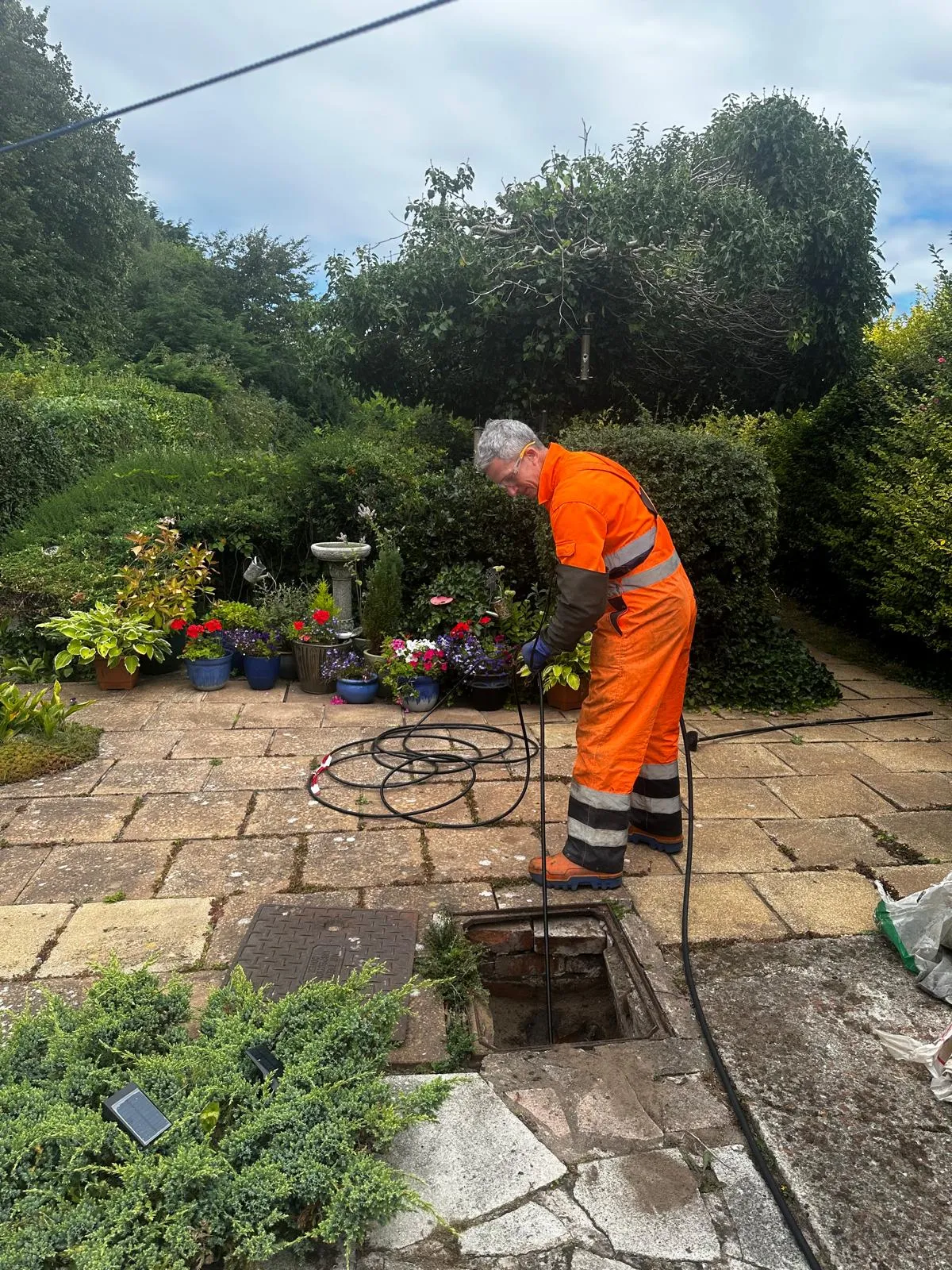 A local Skipton drain specialist performing a drain survey or unblocking service in a home's outdoor space.