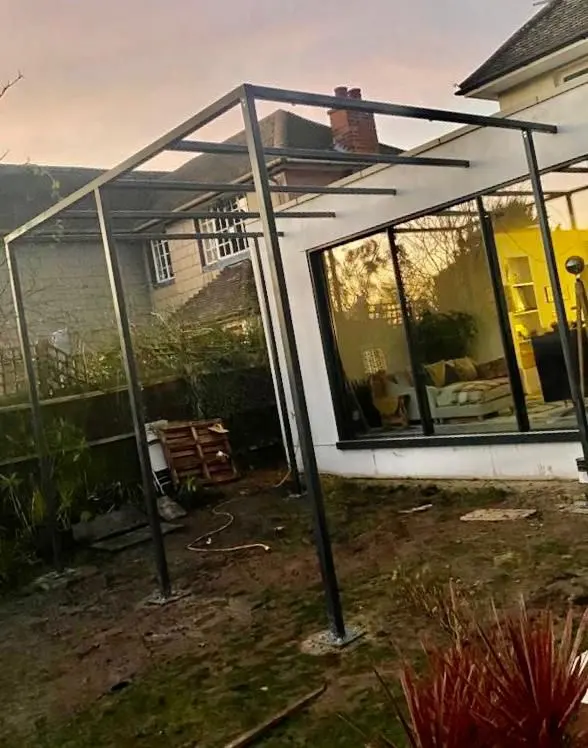 A black steel framework being erected for a home extension or garden structure