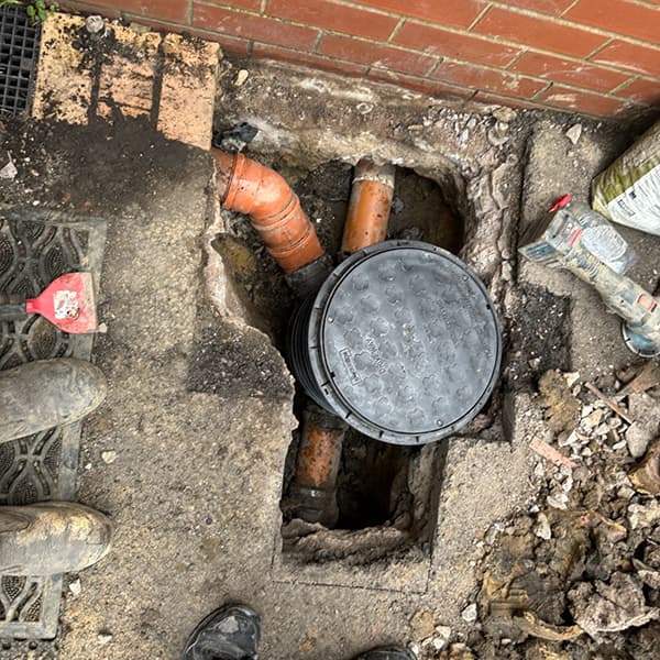 Expert drain excavation and collapsed drain repair showing exposed pipework and a new inspection chamber installation by Drain Medics