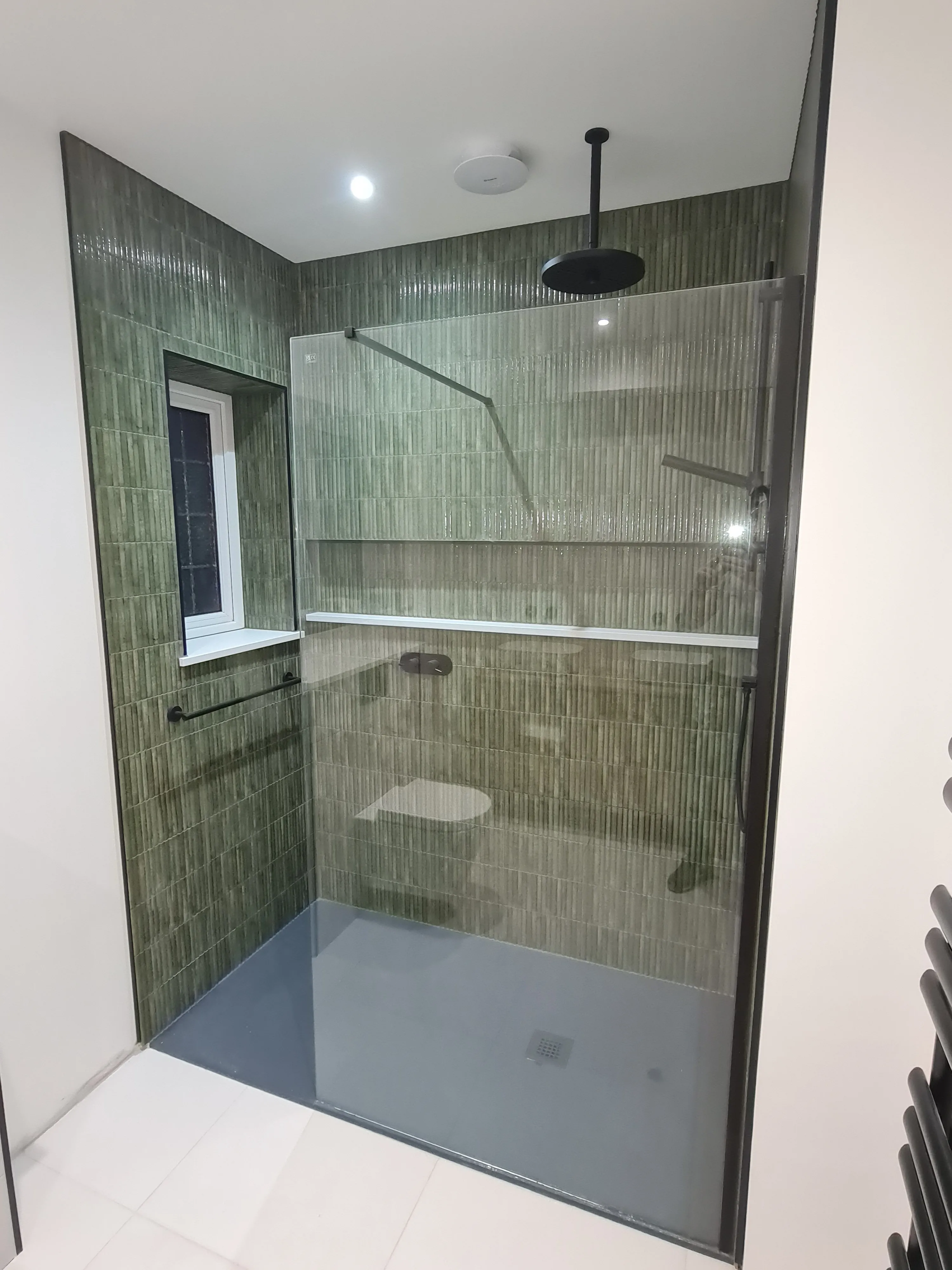 Bespoke luxury walk-in shower with green fluted tiling and matte black hardware by Sands & Vossen in Plymouth.