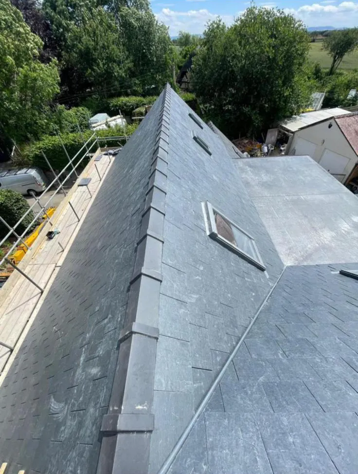 New slate roof installation with capped ridge tiles and roof window in Plymouth