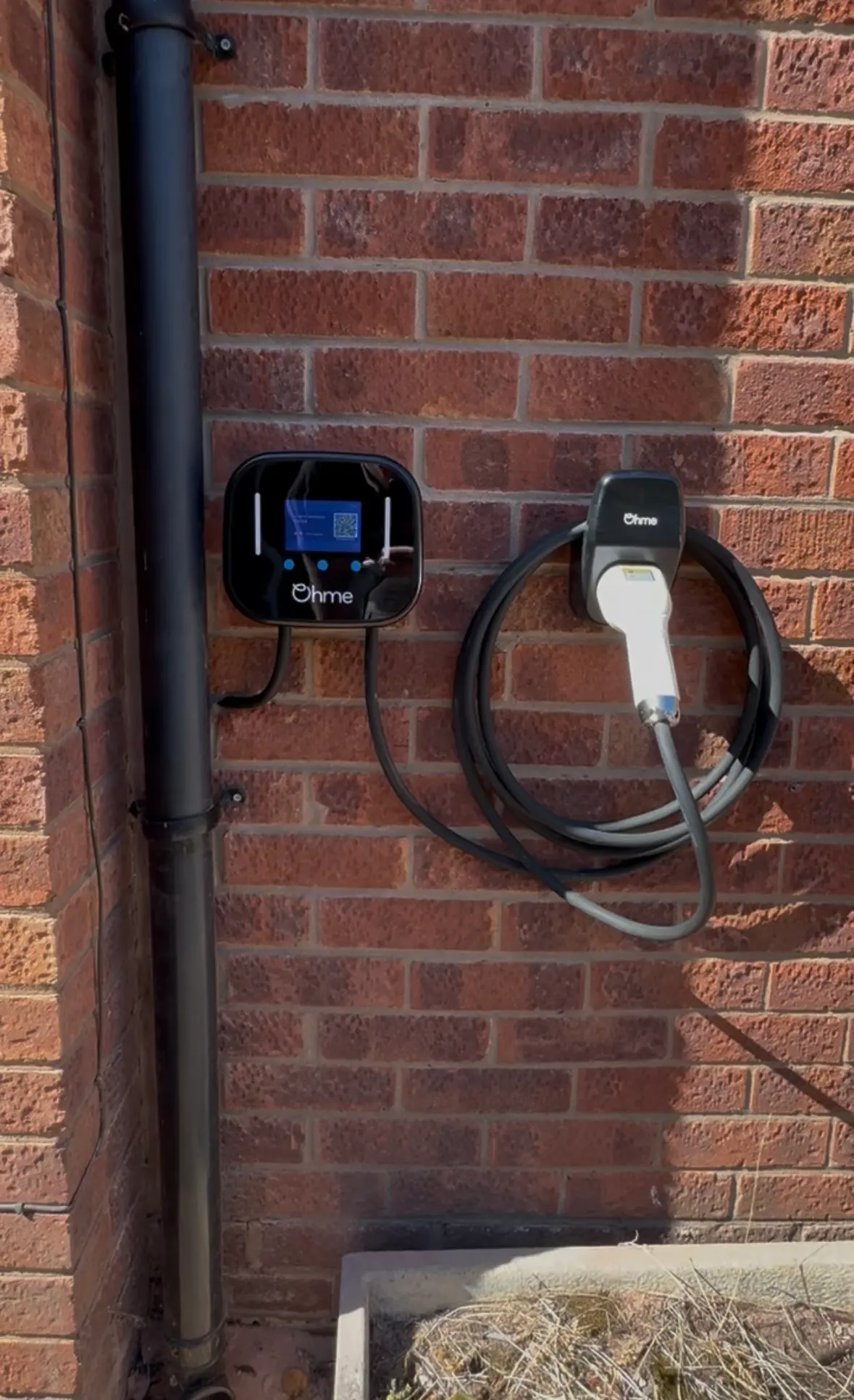 Professional Ohme home EV charger installation on a brick wall in Warrington by JH Electrical Contractors Ltd.